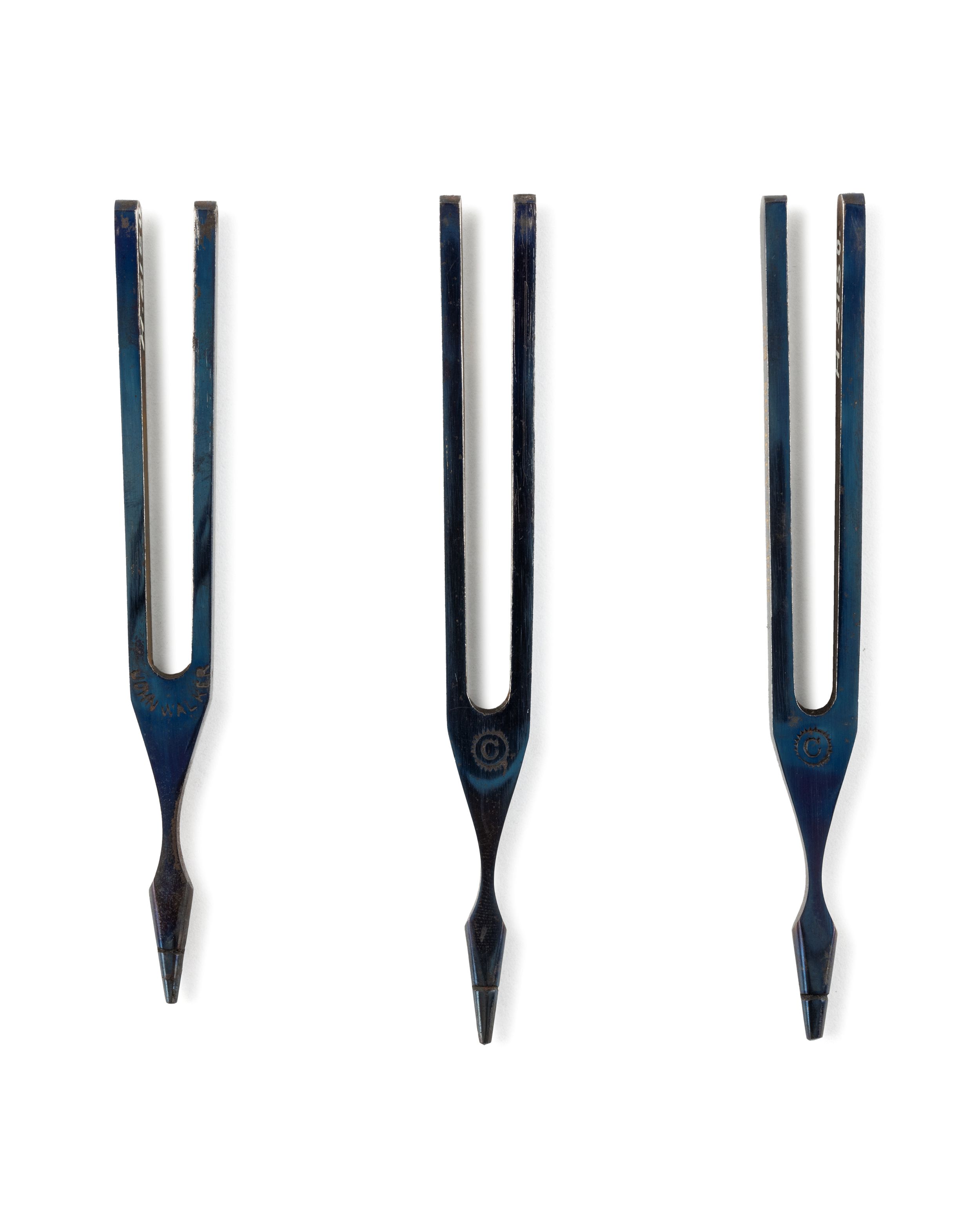 Three black metal tuning forks laid flat in a row.