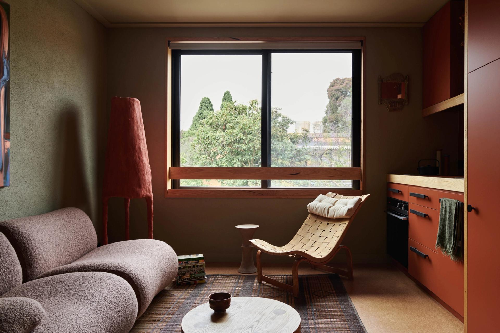 Retro fitted apartment, with lounge, arm chair, window and kitchenette.