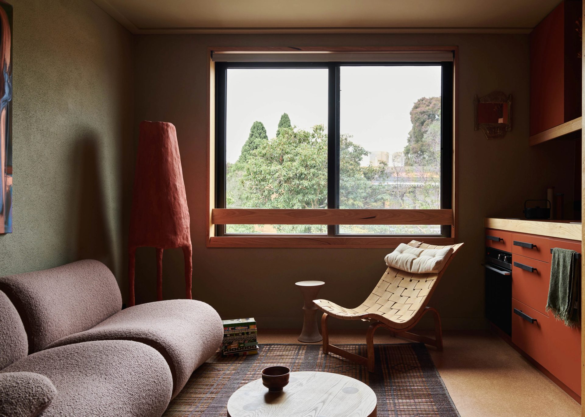 Retro fitted apartment, with lounge, arm chair, window and kitchenette.