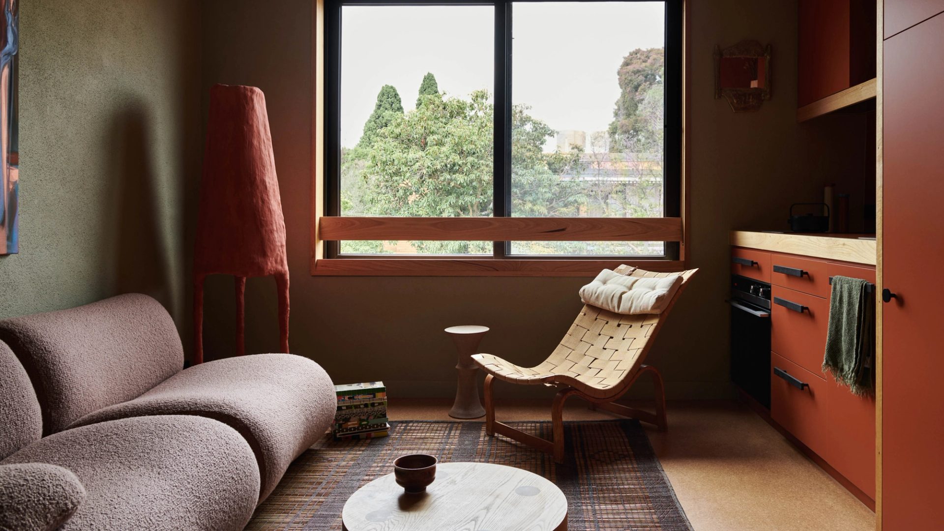 Retro fitted apartment, with lounge, arm chair, window and kitchenette.