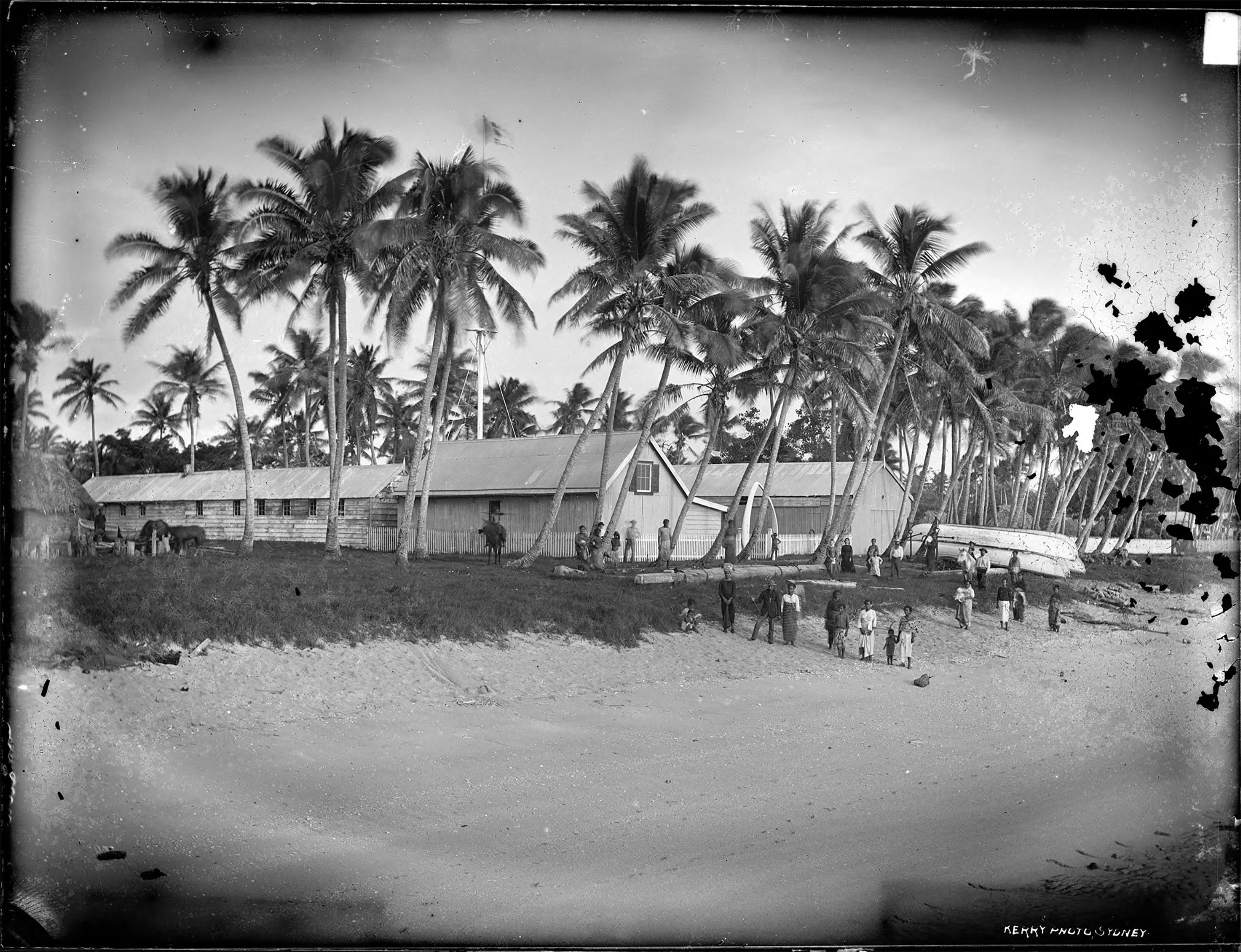 Wooden houses with corrugated iron roofs running alongside a beach.