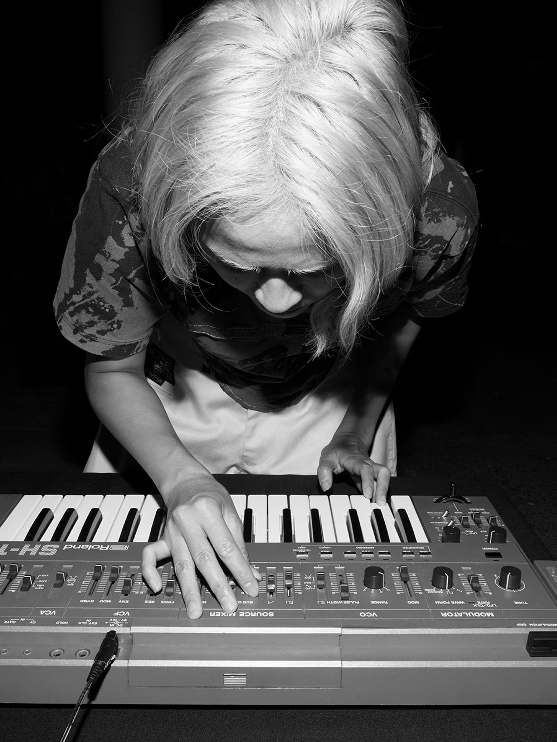 Black and white image of Corin bent over a keyboard.