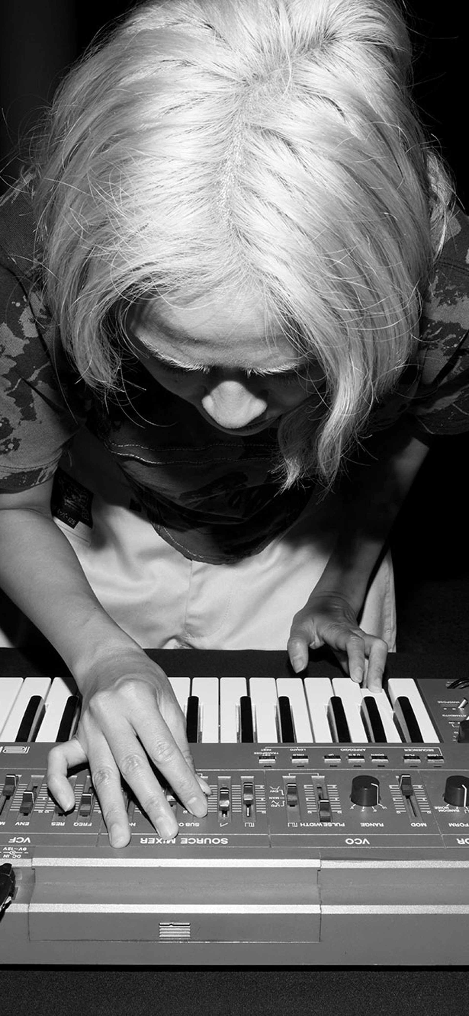 Black and white image of Corin bent over a keyboard.