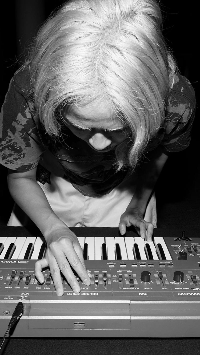 Black and white image of Corin bent over a keyboard.