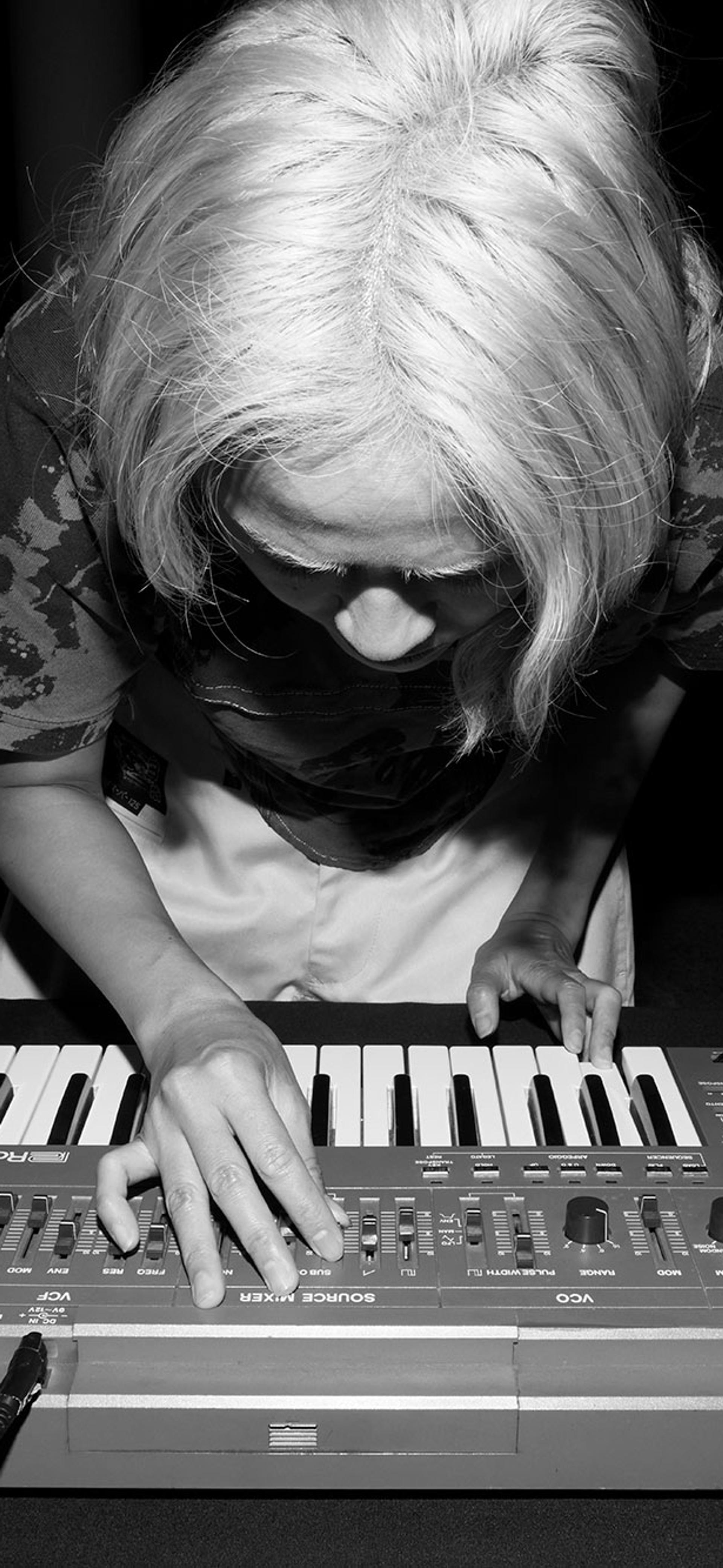 Black and white image of Corin bent over a keyboard.