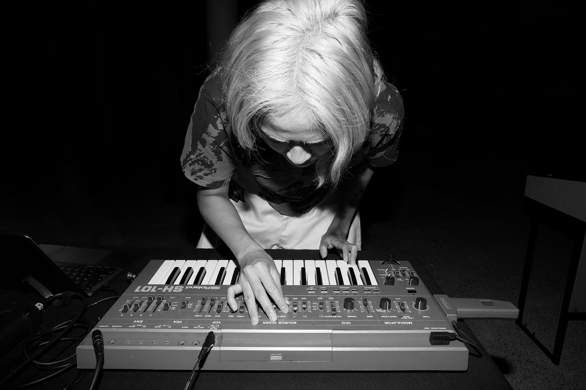 Black and white image of Corin bent over a keyboard.