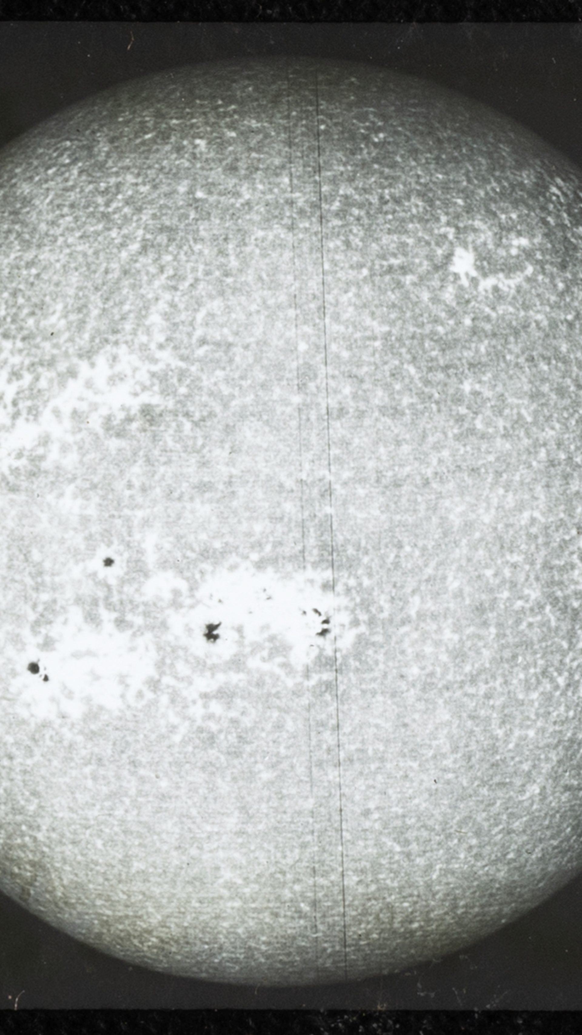 A close up photograph of a glass plate slide showing black and white photo of 'sun's disk (spectroheliogram)', used for teaching astronomy.