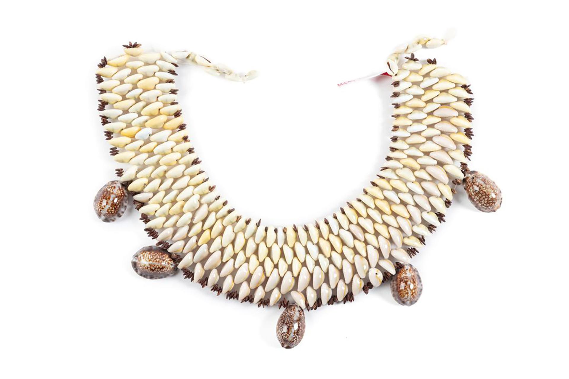 A u-shaped neck collar formed from five layers (one above the other) of cowrie shells tightly bound on clear nylon cord.