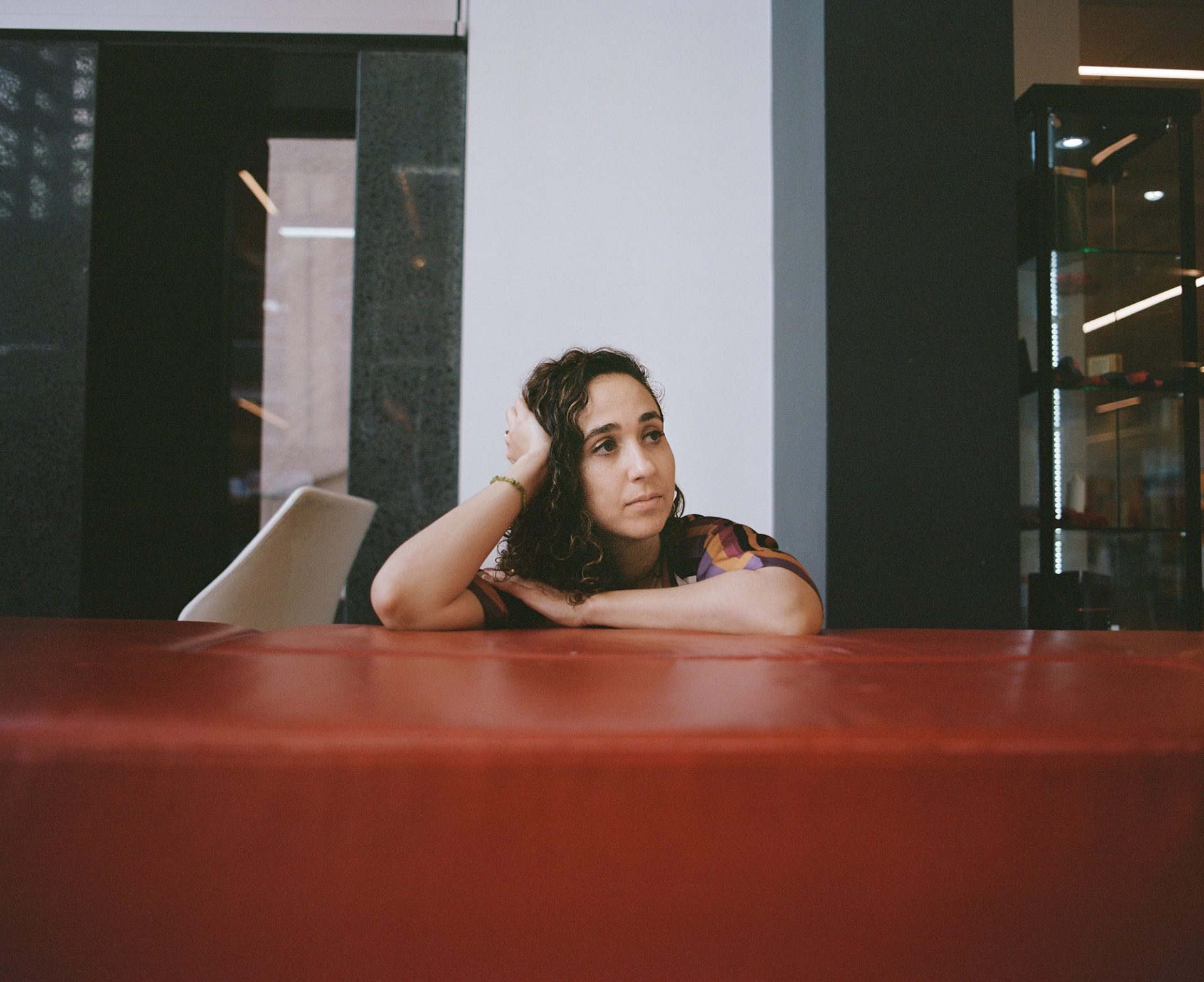 Figure leans on a wall, and looks out of frame.