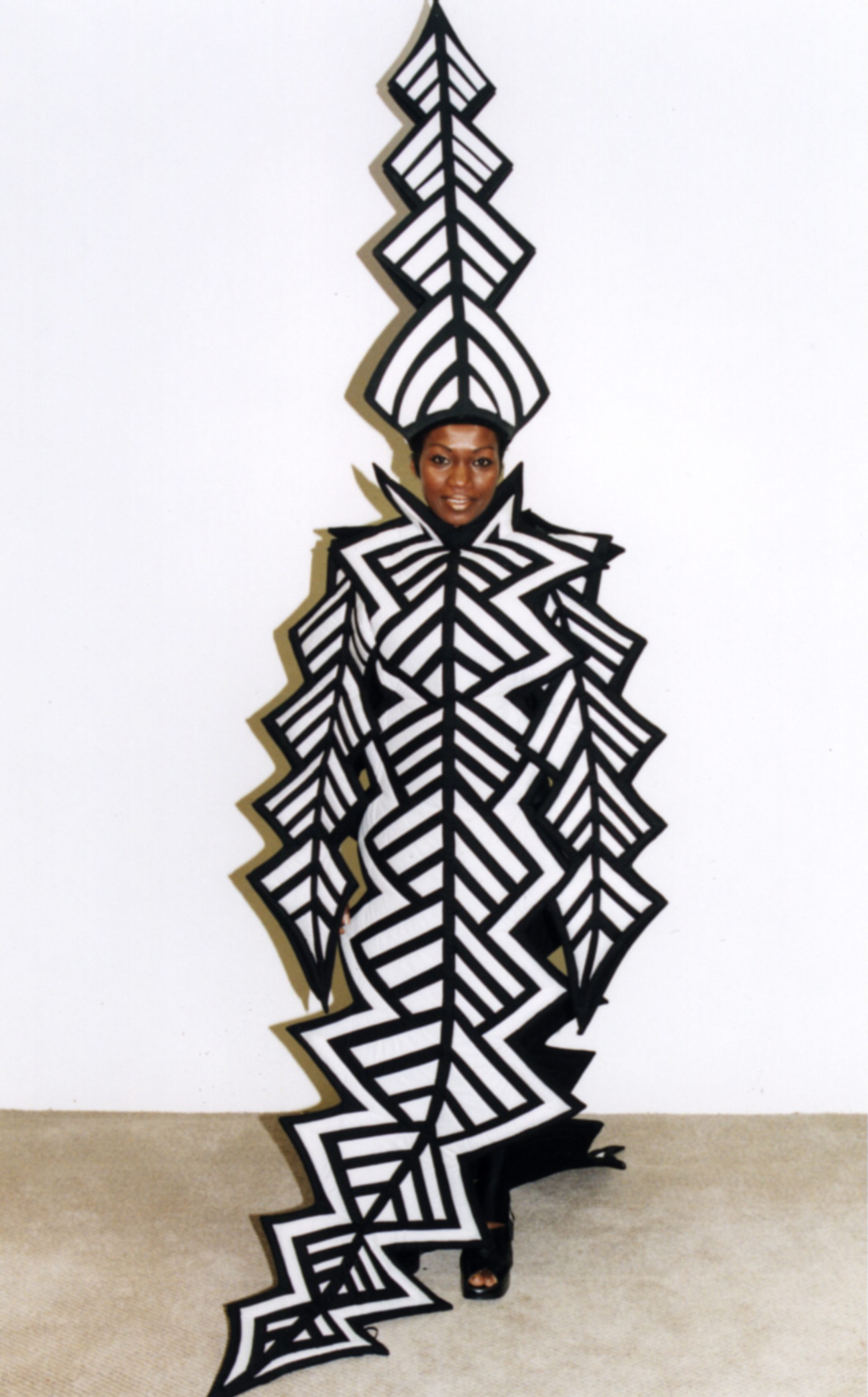 A woman dress in a zig sag black and white patterned costume with a matching tall hat.