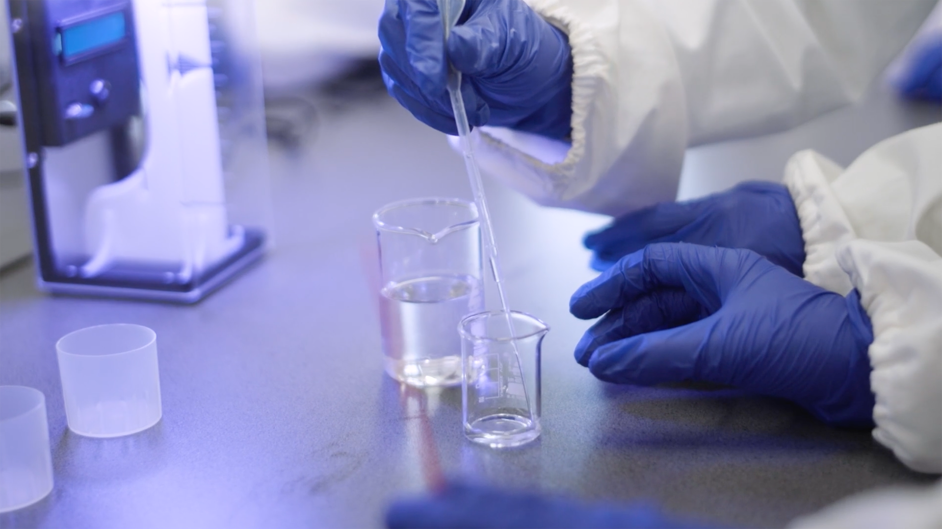 blue gloves on white sleeved arms, with science tools