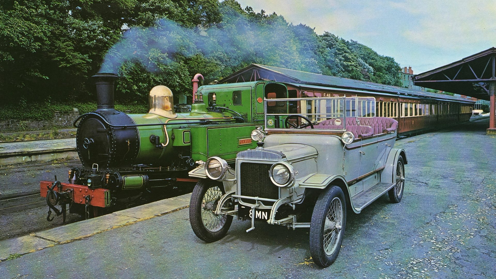 Colour photographic print of a 1914 Daimler and train, cut from calendar or magazine.