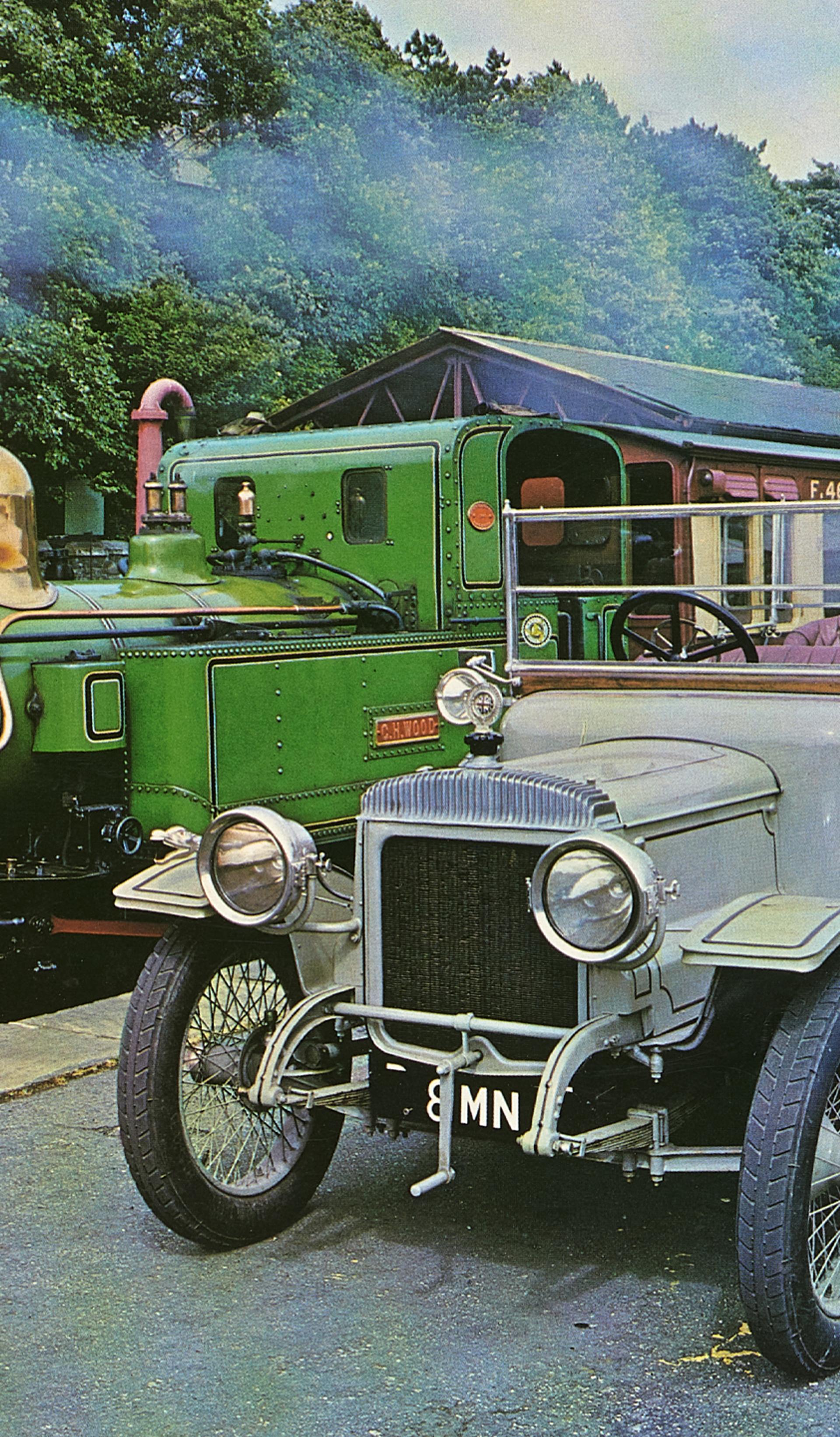 Colour photographic print of a 1914 Daimler and train, cut from calendar or magazine.