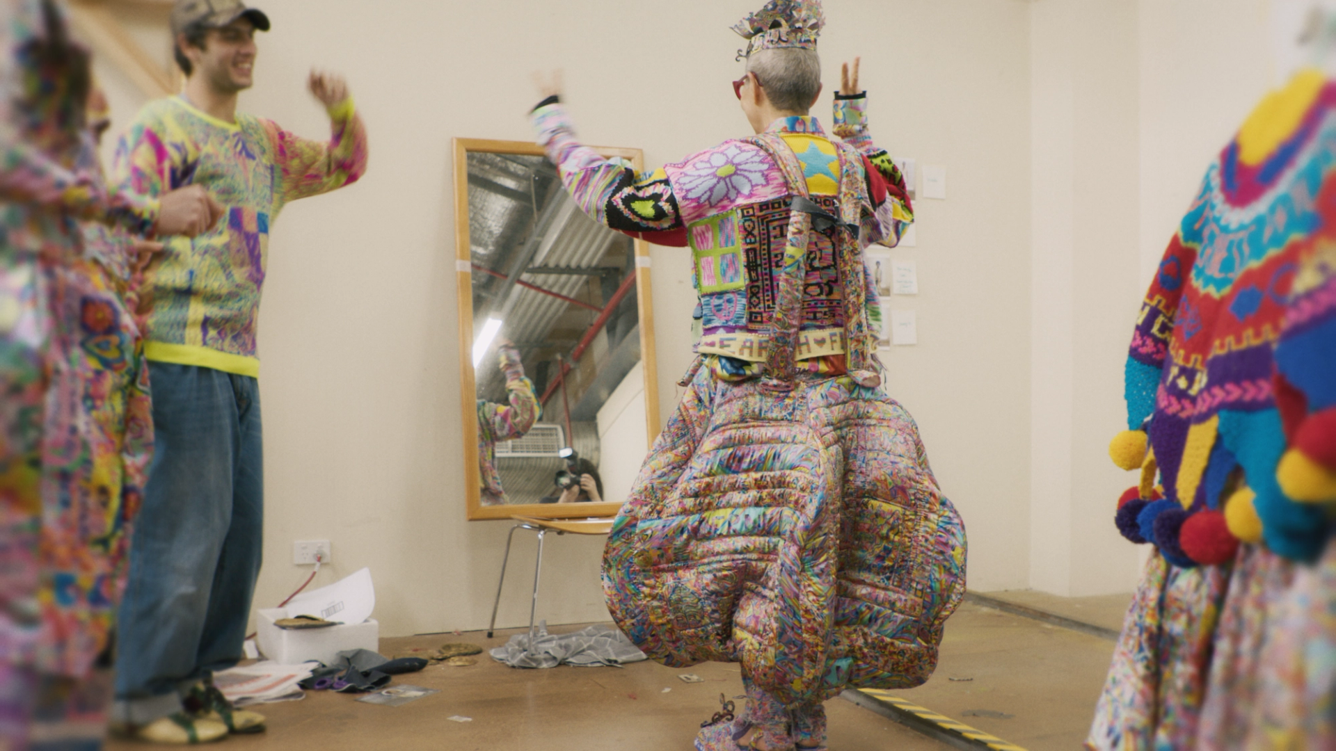 Jenny Kee wearing a dress and jacket by Jordan Gogos standing in front of a mirror.