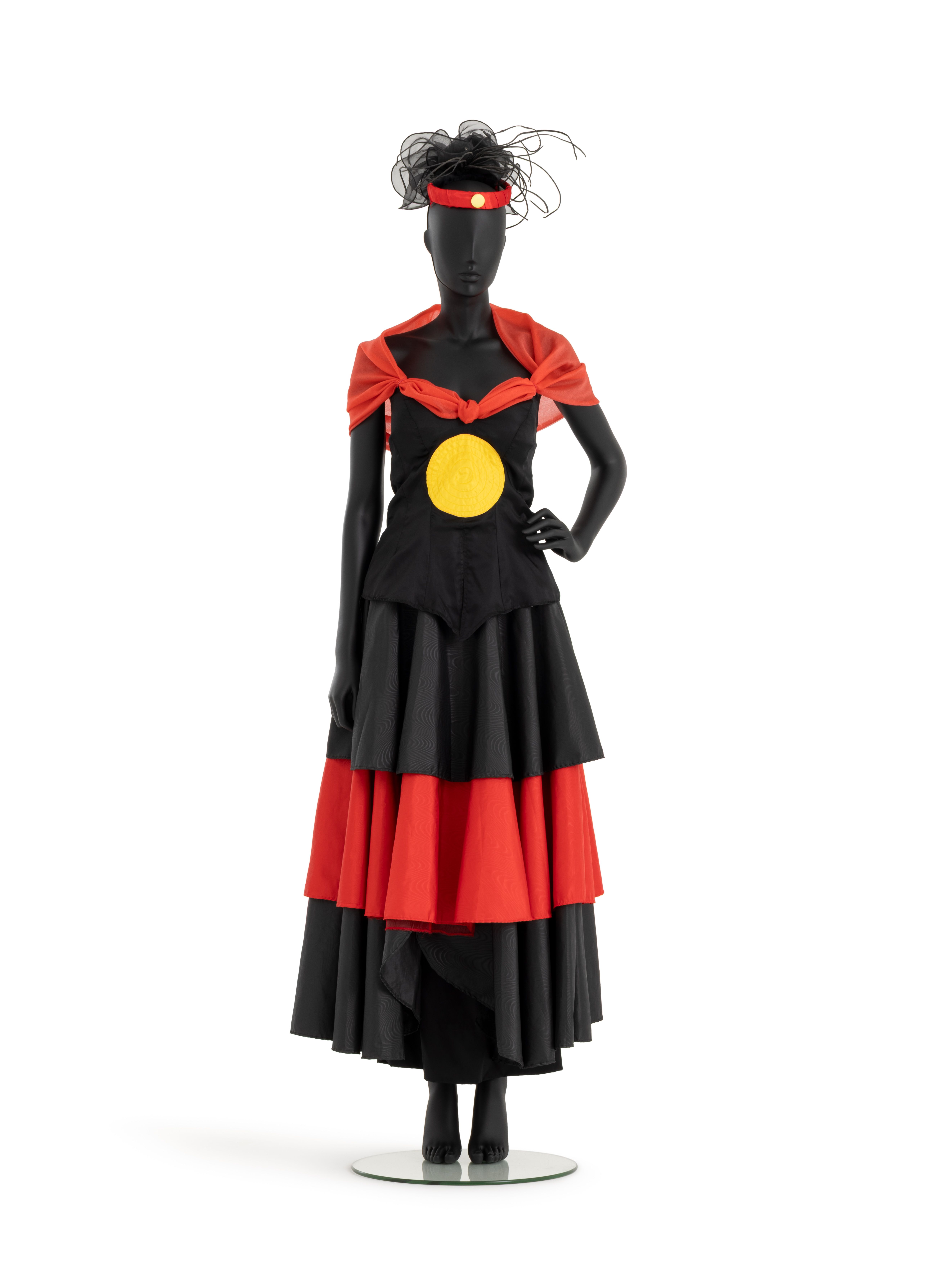 Outfit of red and black taffeta consisting of a tiered circular skirt, bodice with yellow sun appliqued at centre front and red shawl collar.