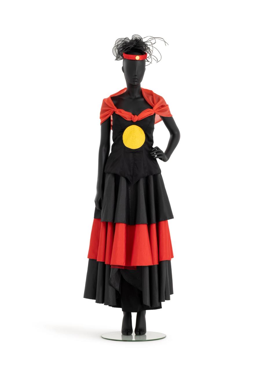 Outfit of red and black taffeta consisting of a tiered circular skirt, bodice with yellow sun appliqued at centre front and red shawl collar.