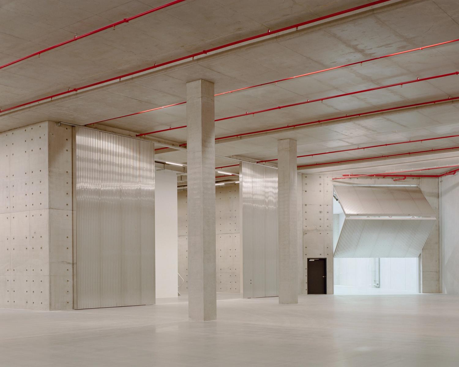 A huge concrete space with two large columns in the middle and a large folding door on the right.