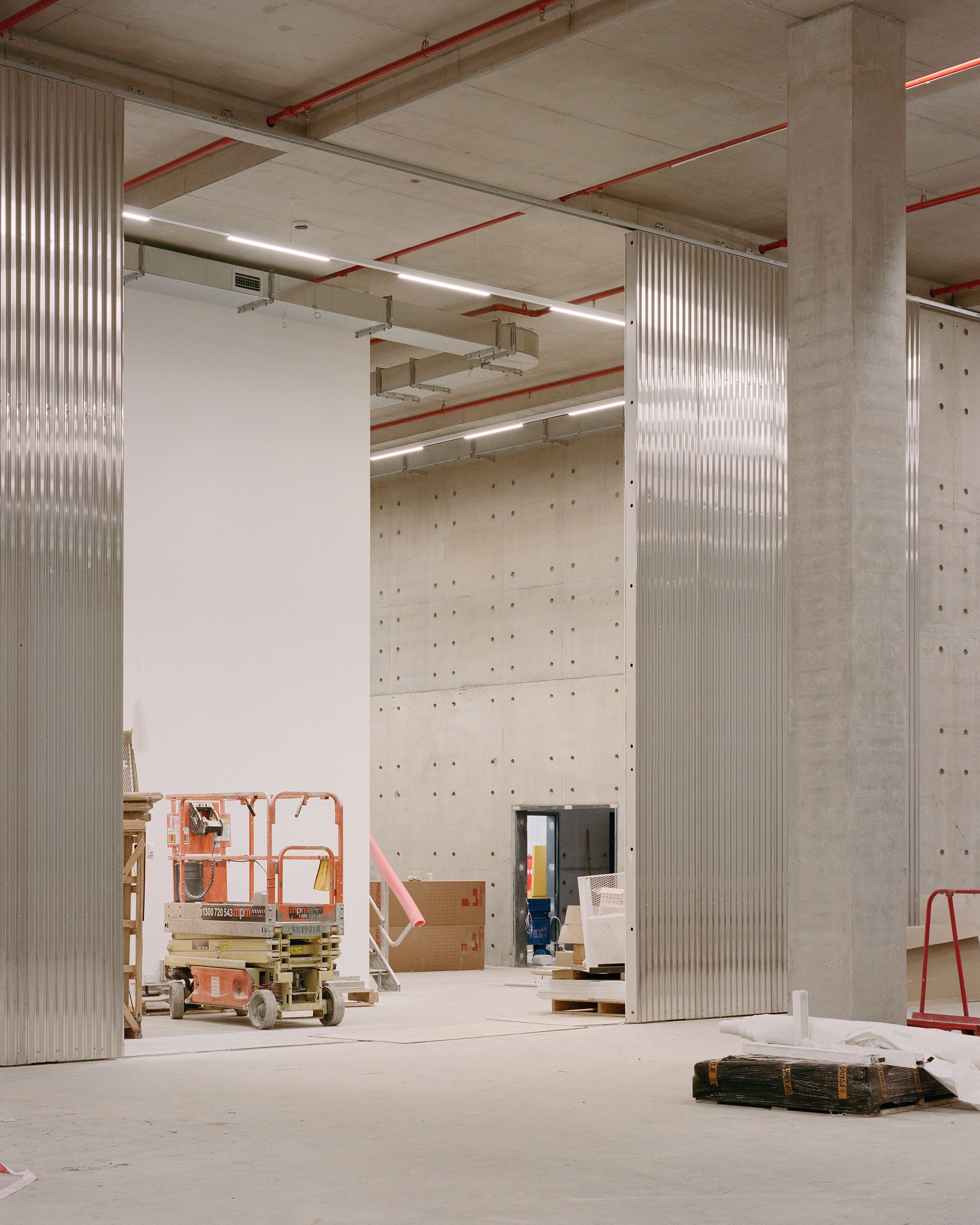 Walkways and open metal doors with a construction scissor lift and piles of material