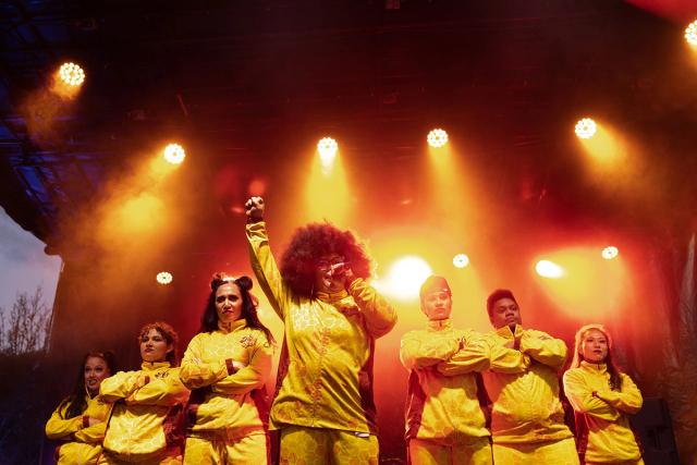 Group in yellow tracksuits on stage.