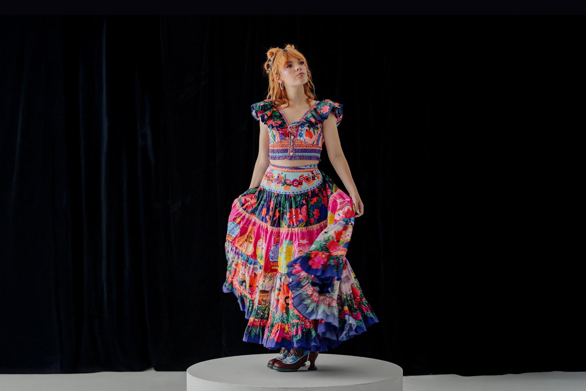 Activist Chloe Hayden posed in the centre, wearing a vibrant, multi-patterned dress against a black background.
