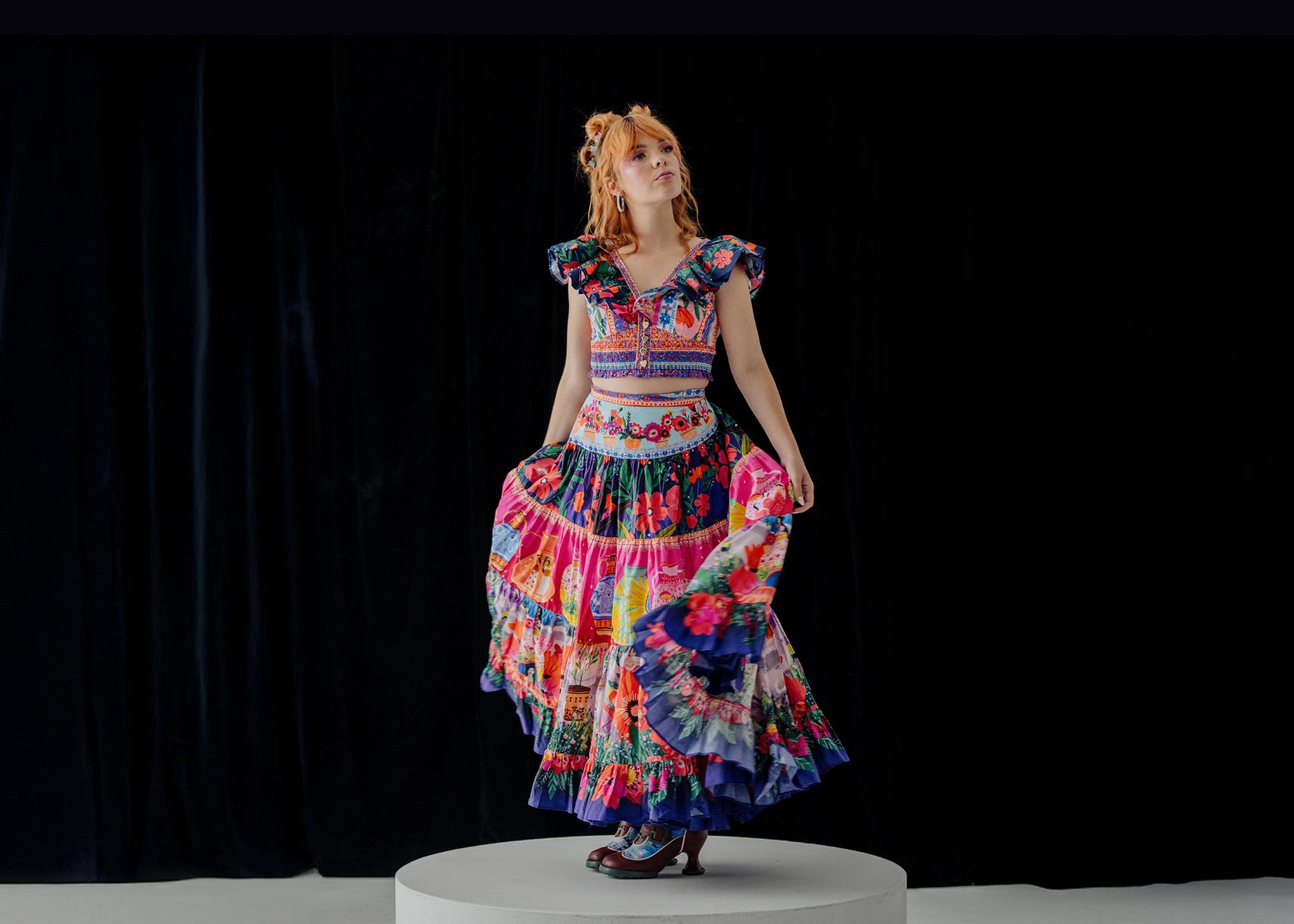 Activist Chloe Hayden posed in the centre, wearing a vibrant, multi-patterned dress against a black background.