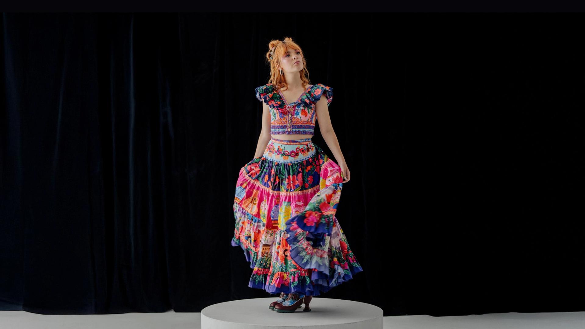 Activist Chloe Hayden posed in the centre, wearing a vibrant, multi-patterned dress against a black background.