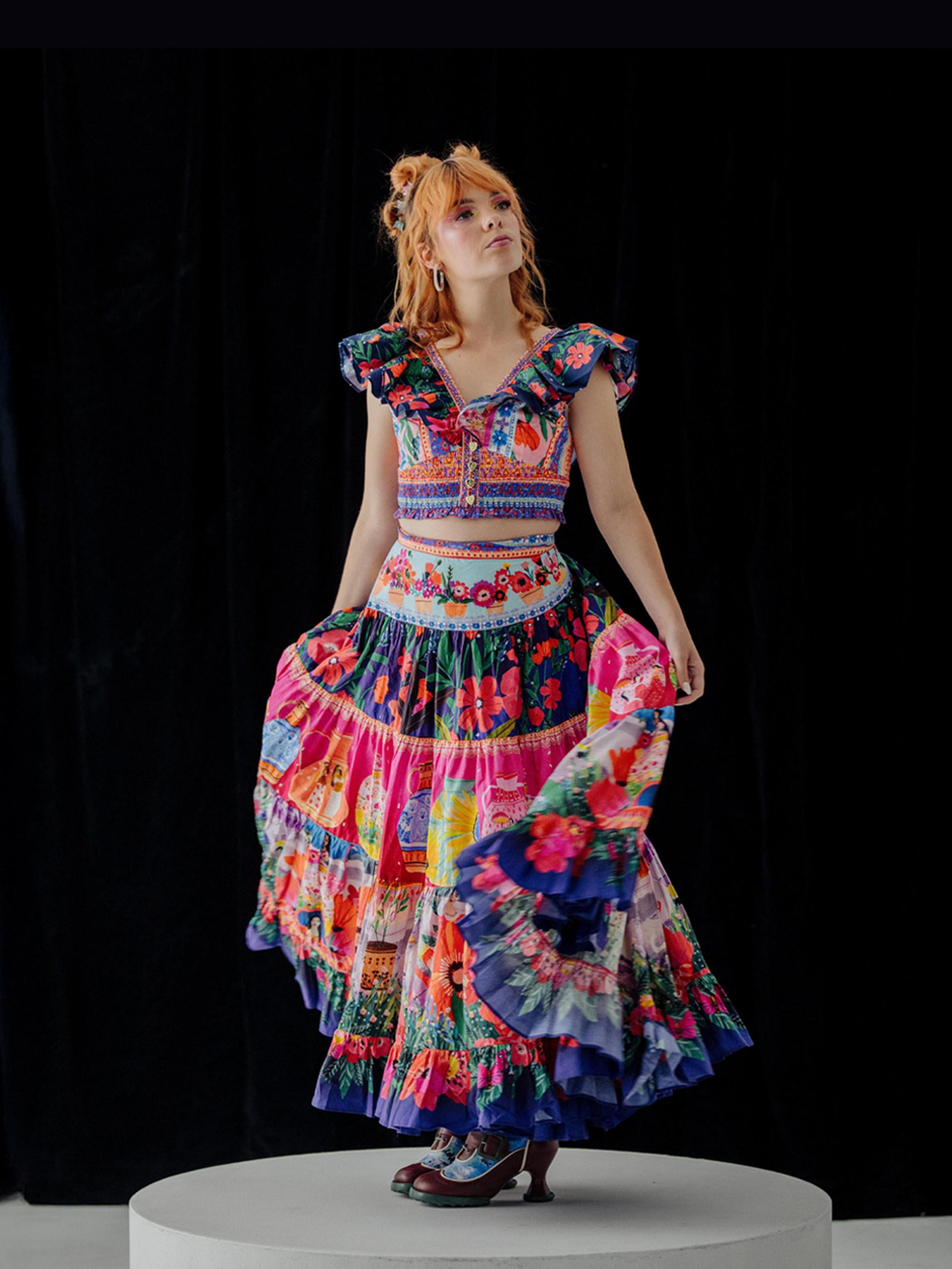 Activist Chloe Hayden posed in the centre, wearing a vibrant, multi-patterned dress against a black background.