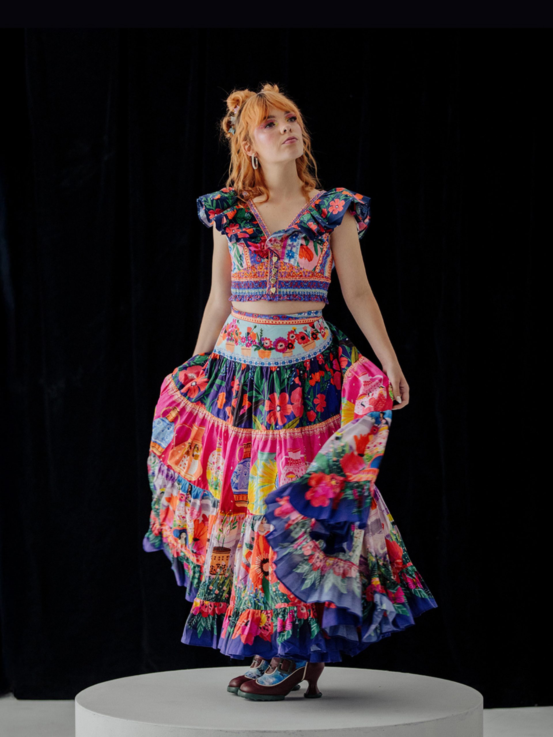Activist Chloe Hayden posed in the centre, wearing a vibrant, multi-patterned dress against a black background.