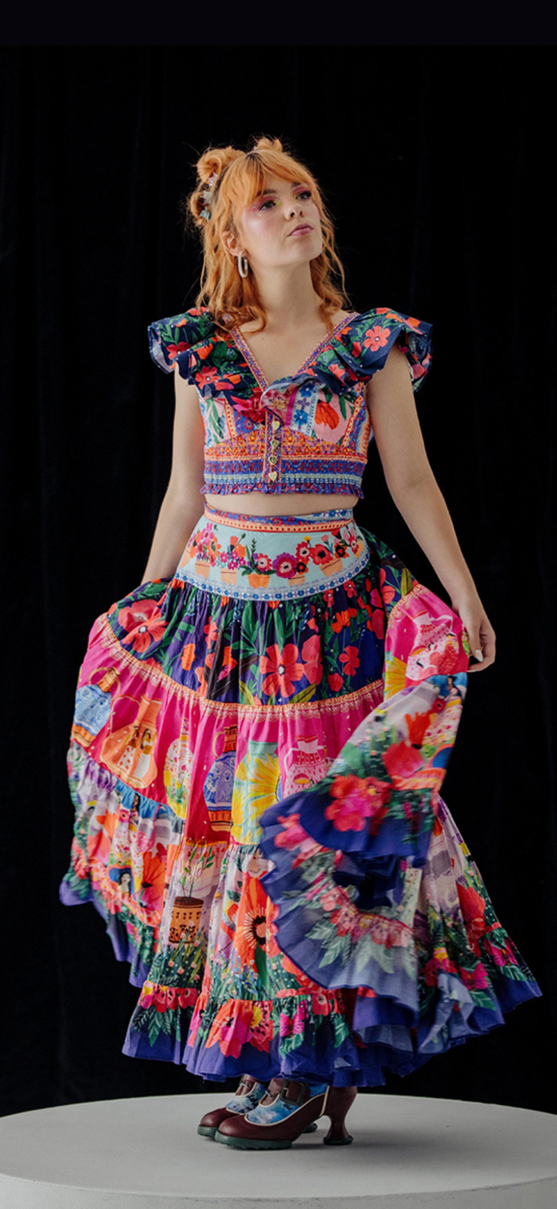 Activist Chloe Hayden posed in the centre, wearing a vibrant, multi-patterned dress against a black background.