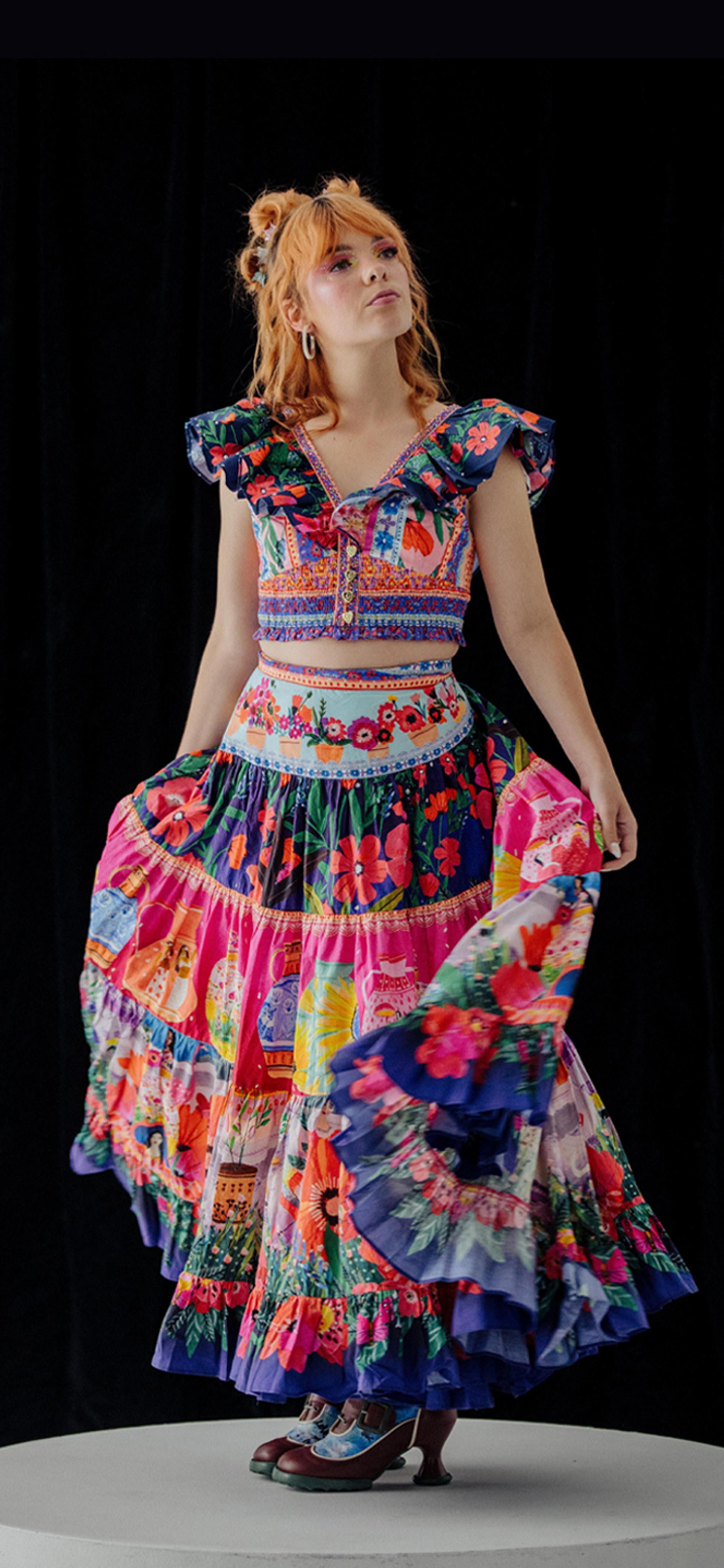 Activist Chloe Hayden posed in the centre, wearing a vibrant, multi-patterned dress against a black background.