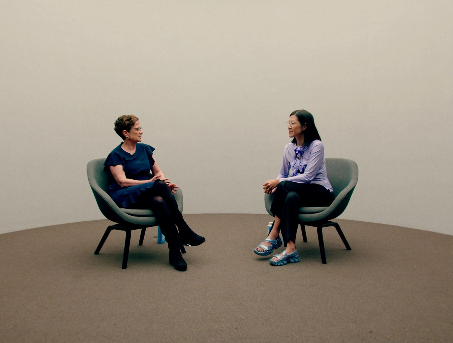 Two women sit in chairs conversing.