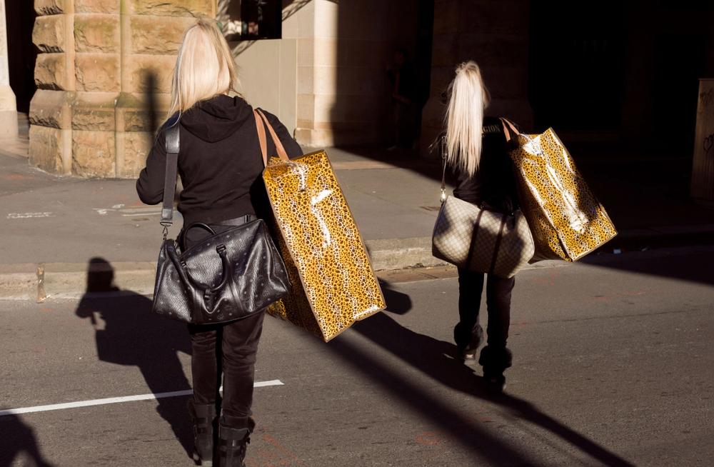 Two figures with blonde hair walk through the Haymarket carrying leopard print bags.