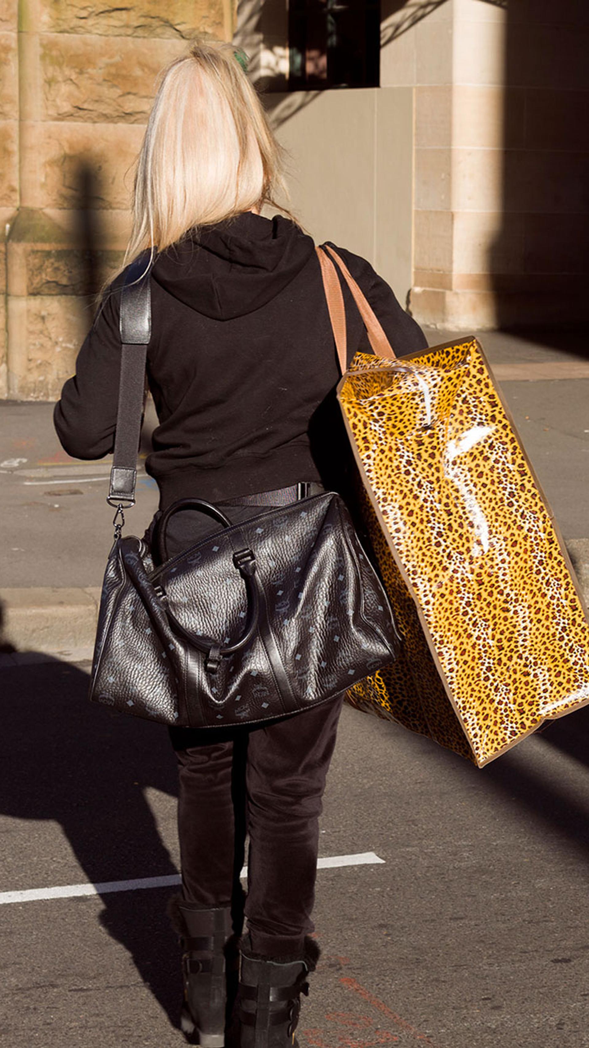 Two figures with blonde hair walk through the Haymarket carrying leopard print bags.