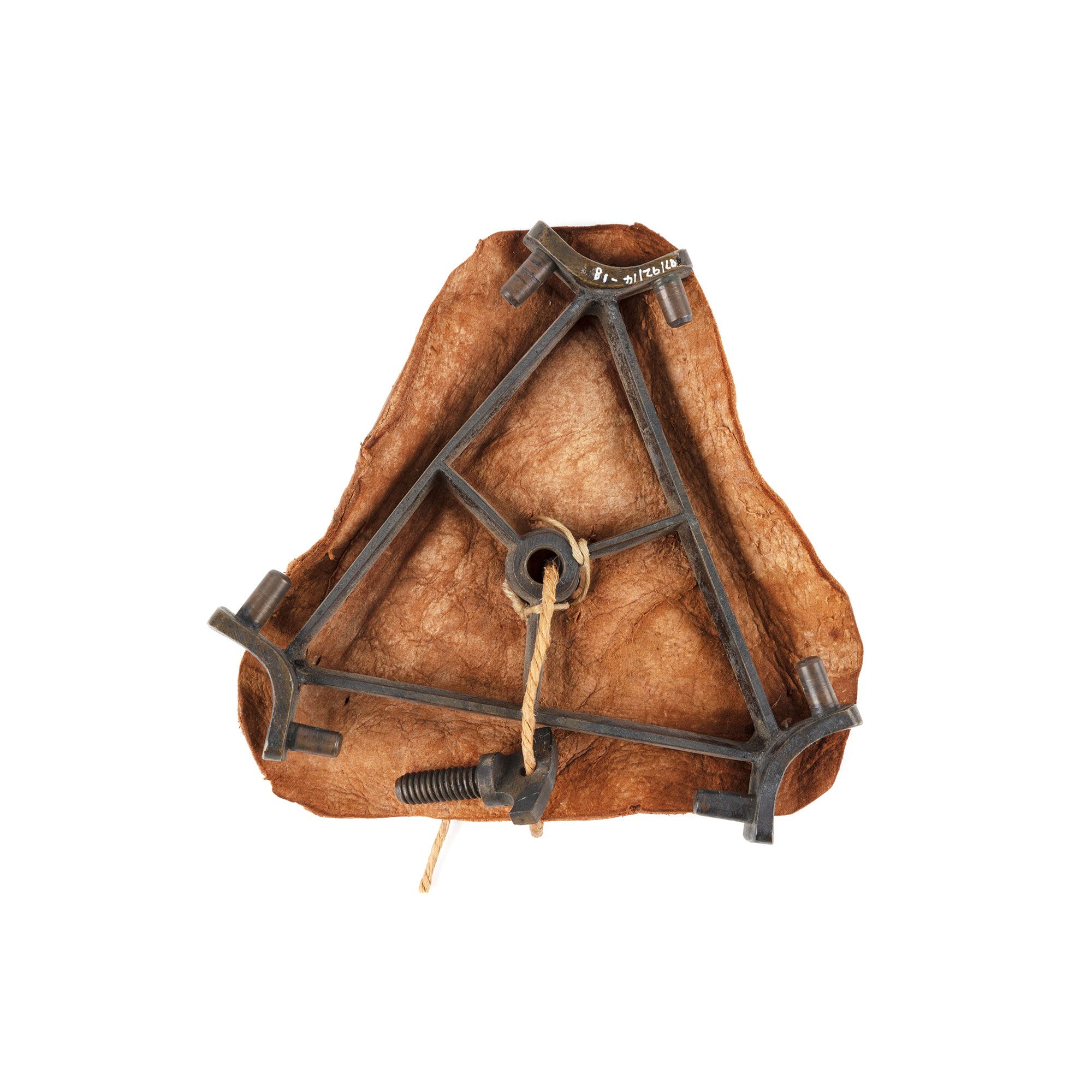 A metal triangle frame with a bolt tied to it with string. Underneath is a leather cover.
