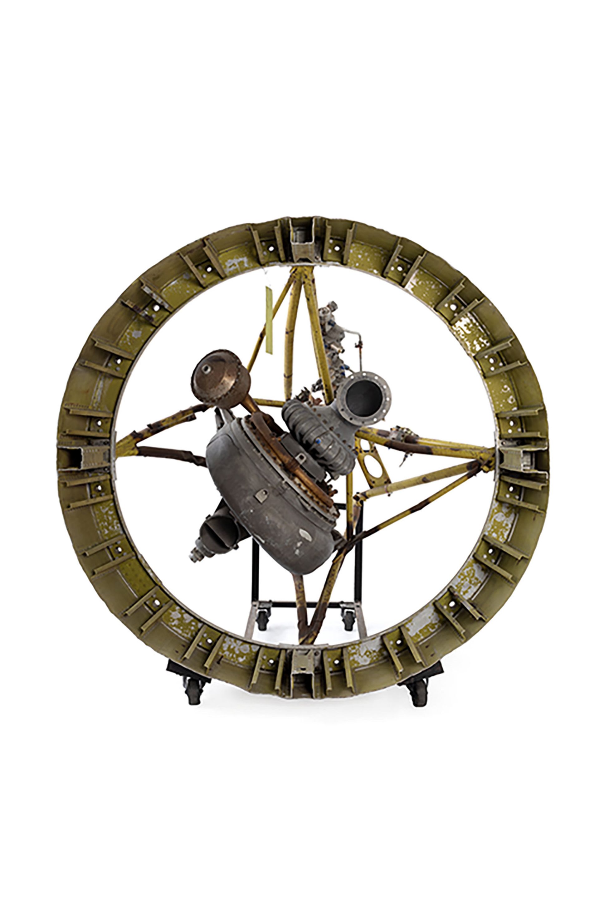 A rocket engine composed on a large metal circular frame with an engine secured from four points in the centre.