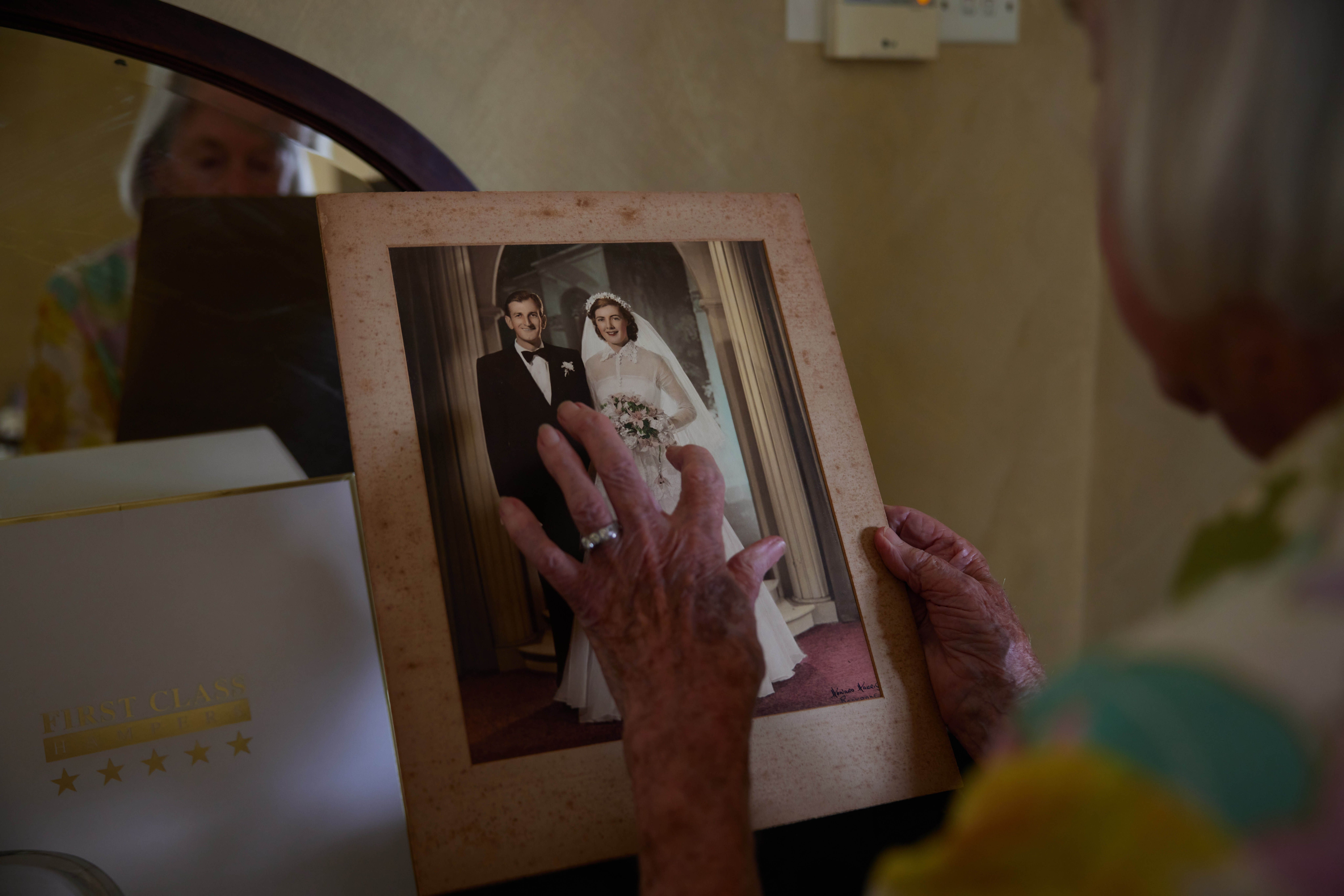 An elderly woman holds her wedding photo.