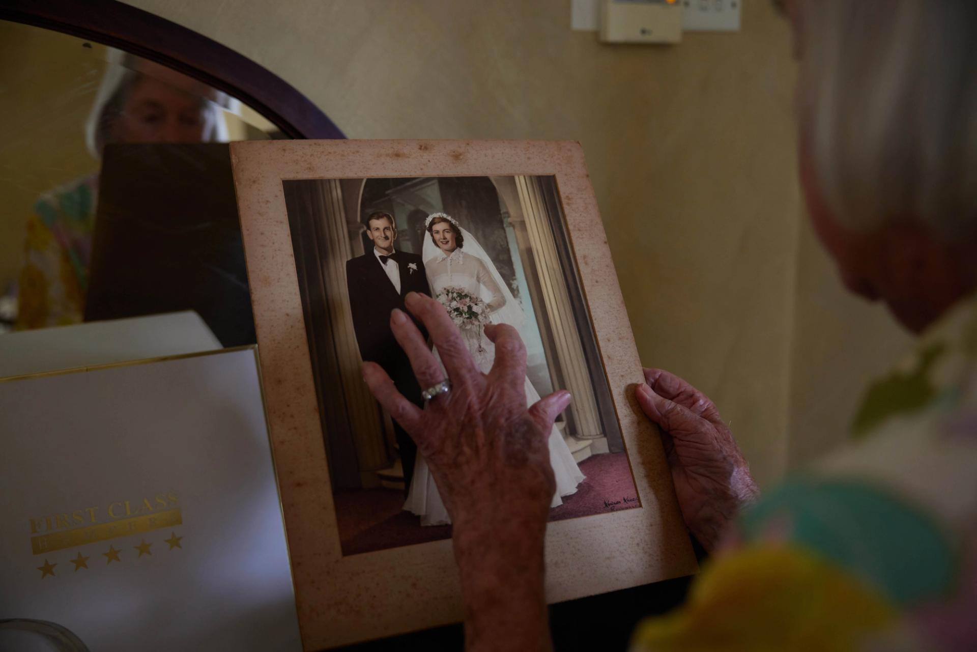 An elderly woman holds her wedding photo.