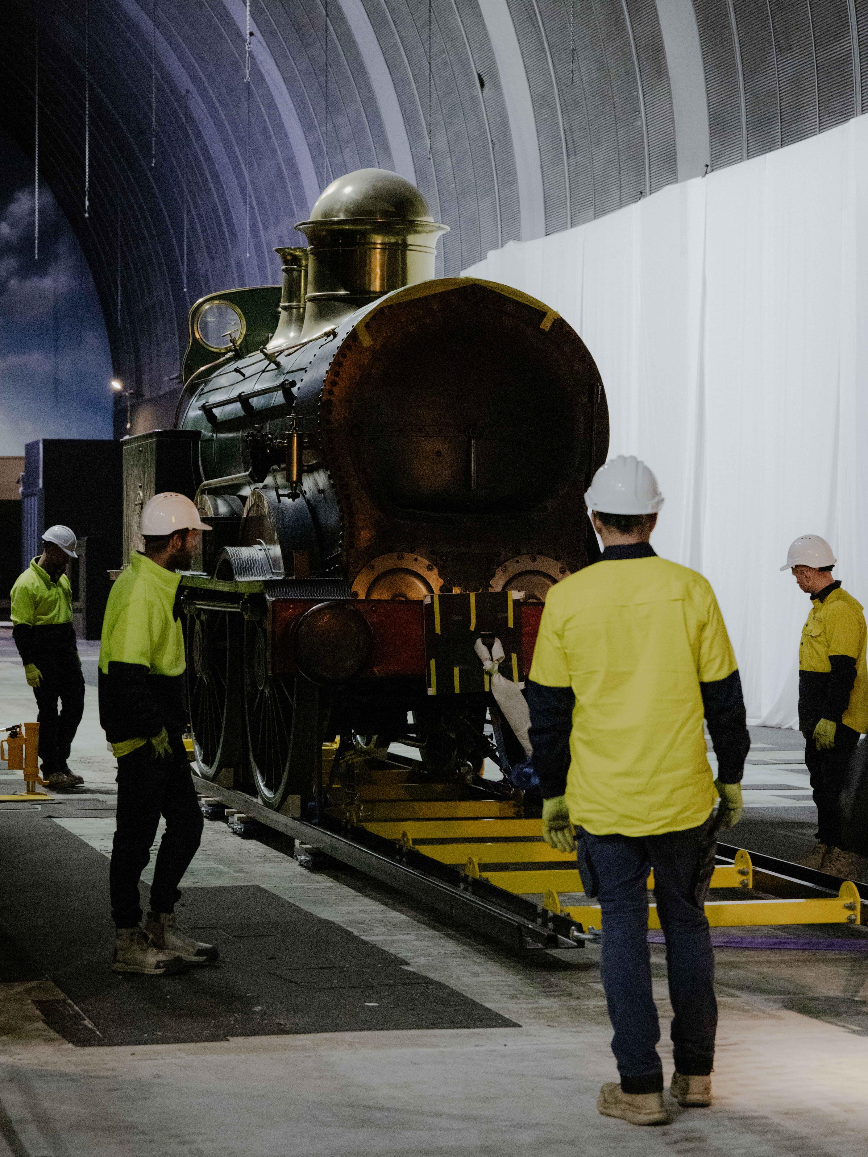 Train on a track with trades people surrounding it.