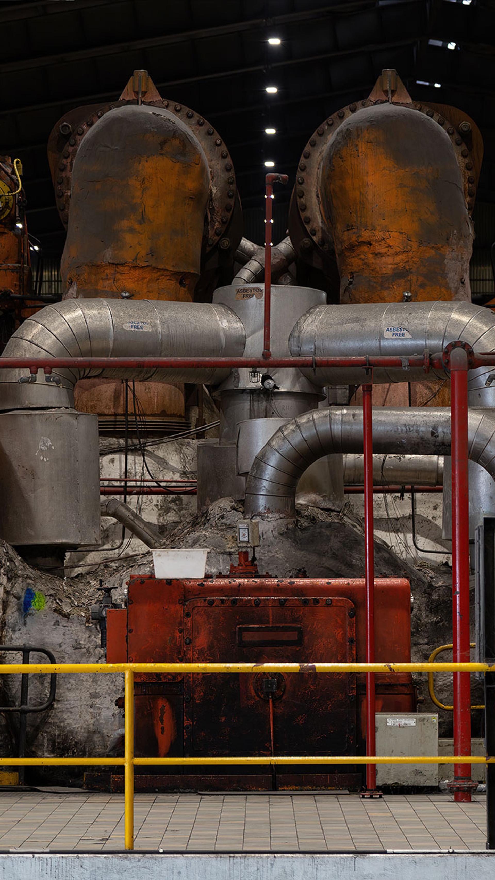 Mechanical and industrial equipment in colours of red, silver and orange sit behind a yellow safety fence.