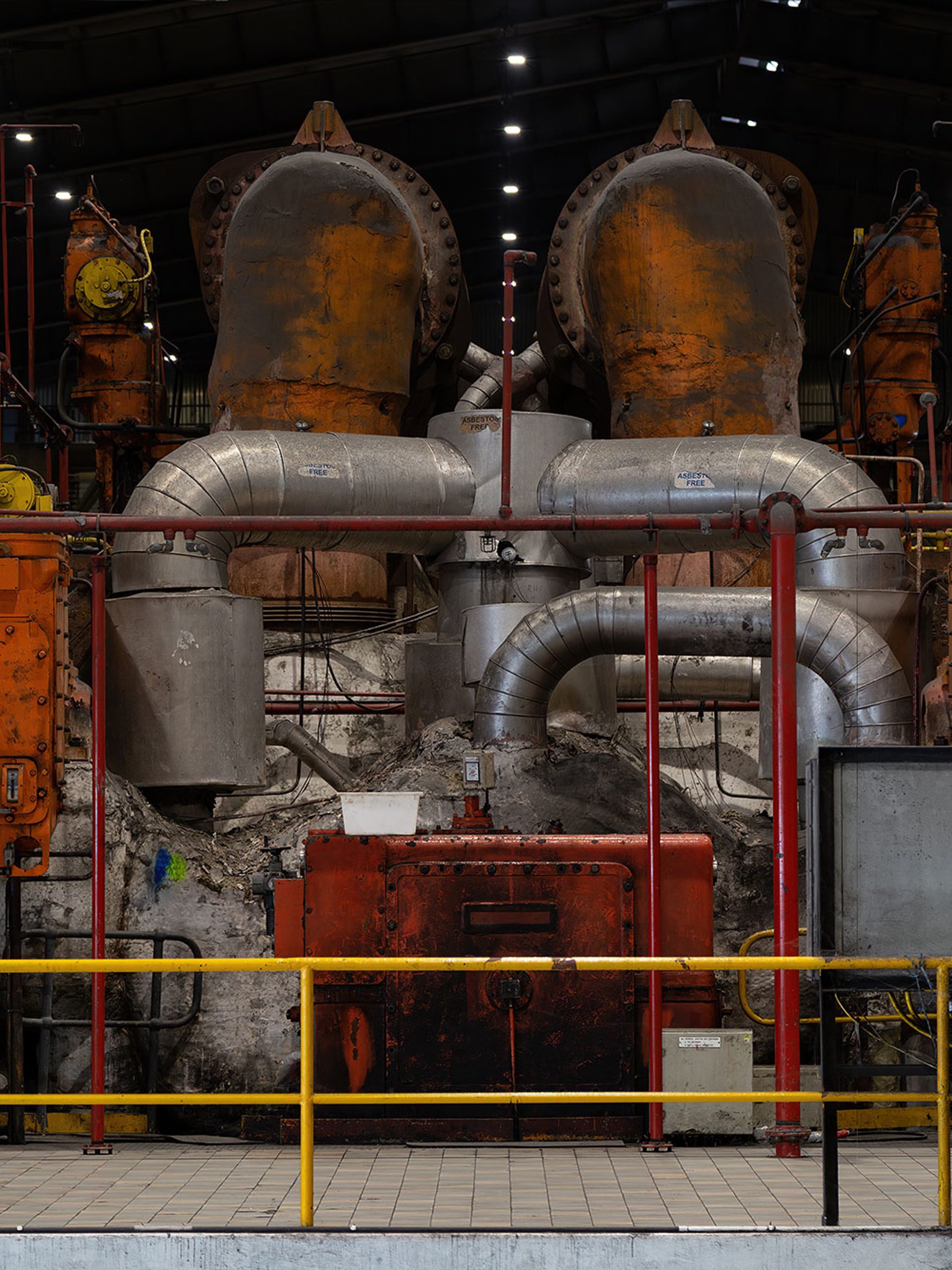 Mechanical and industrial equipment in colours of red, silver and orange sit behind a yellow safety fence.