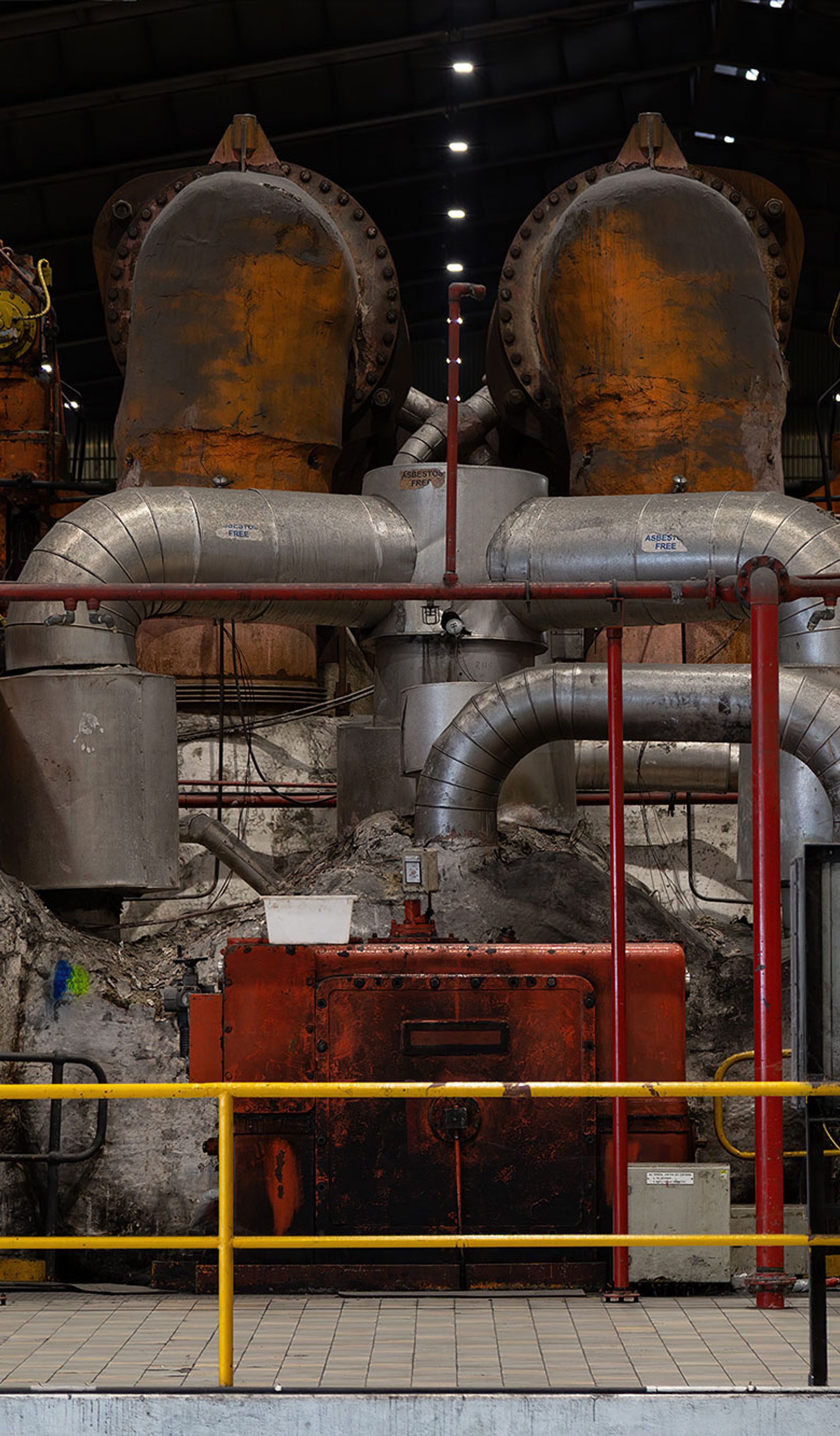 Mechanical and industrial equipment in colours of red, silver and orange sit behind a yellow safety fence.