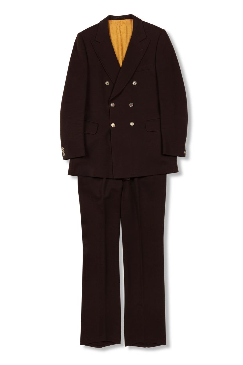 A dark red mens suit of a blazer jacket and trousers made with wool and silk, the inside lining of the blazer uses a bright yellow silk fabric and silver gold buttons.