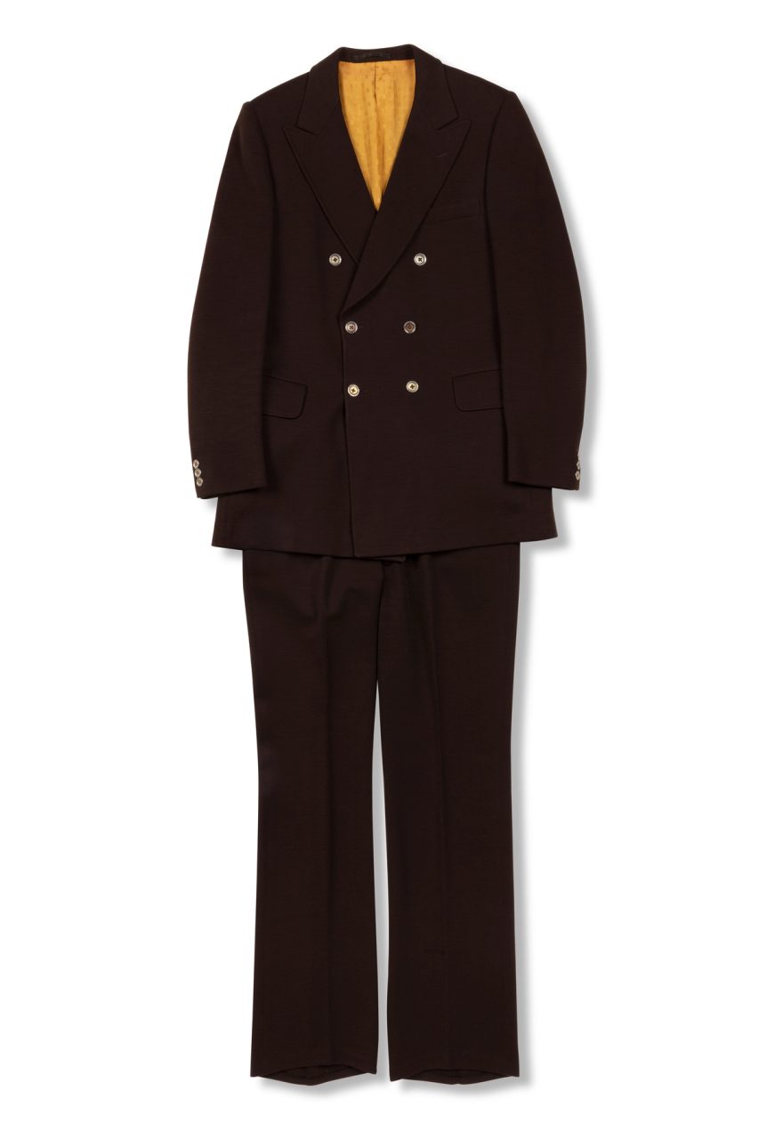 A dark red mens suit of a blazer jacket and trousers made with wool and silk, the inside lining of the blazer uses a bright yellow silk fabric and silver gold buttons.