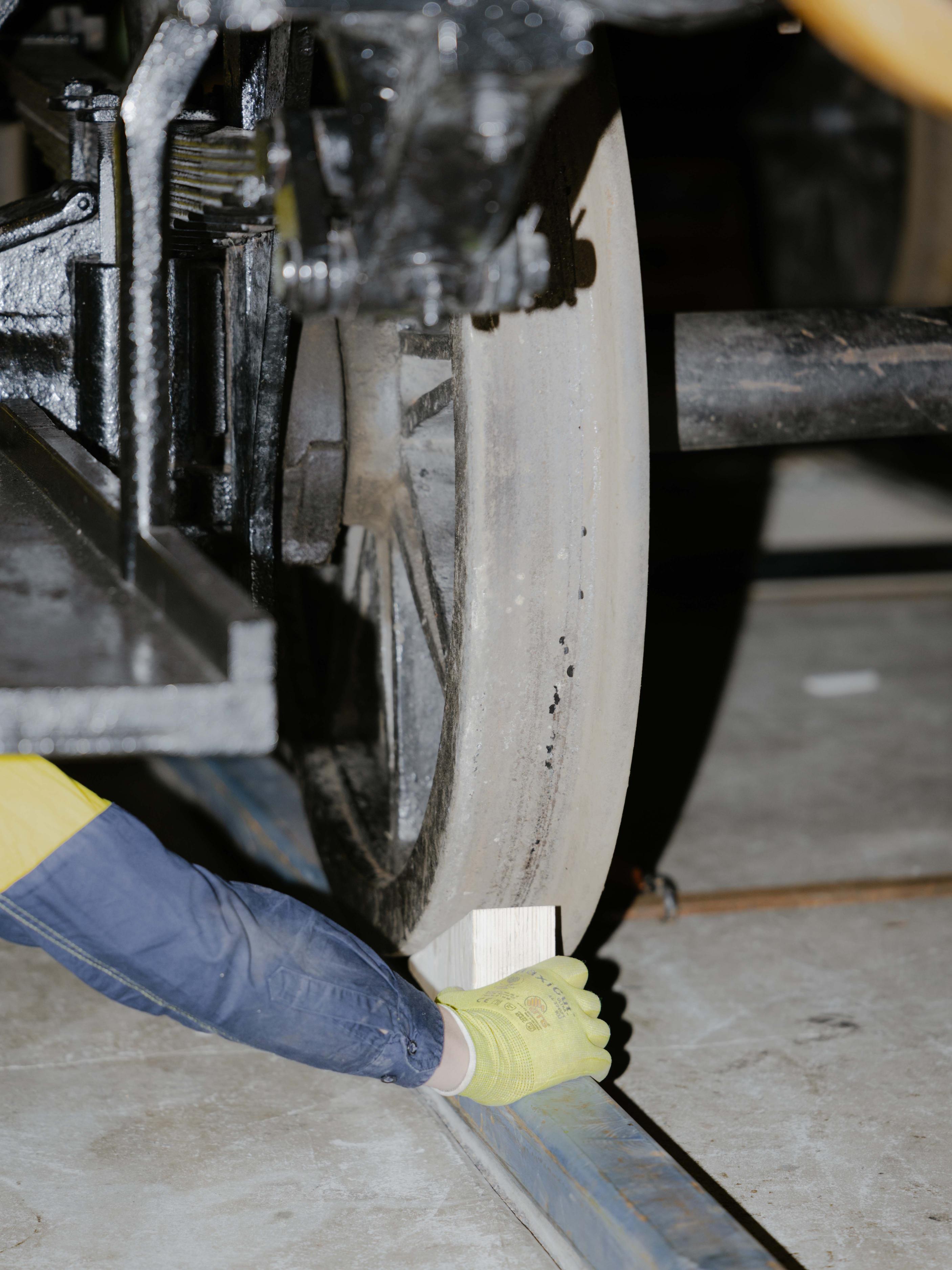 Hand lodges wedge under a steel wheel.