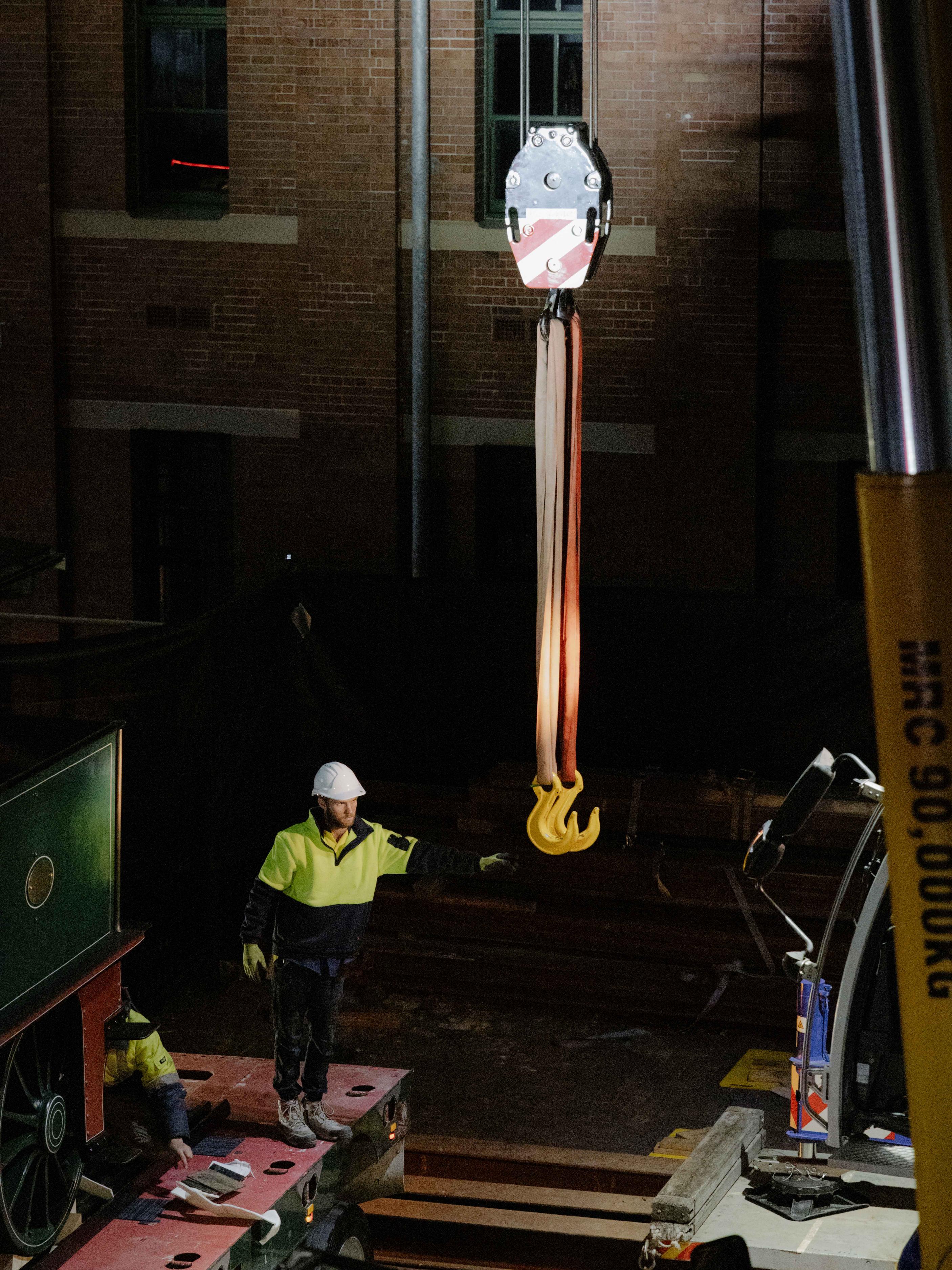 Trades person reaching for a crane's hook.