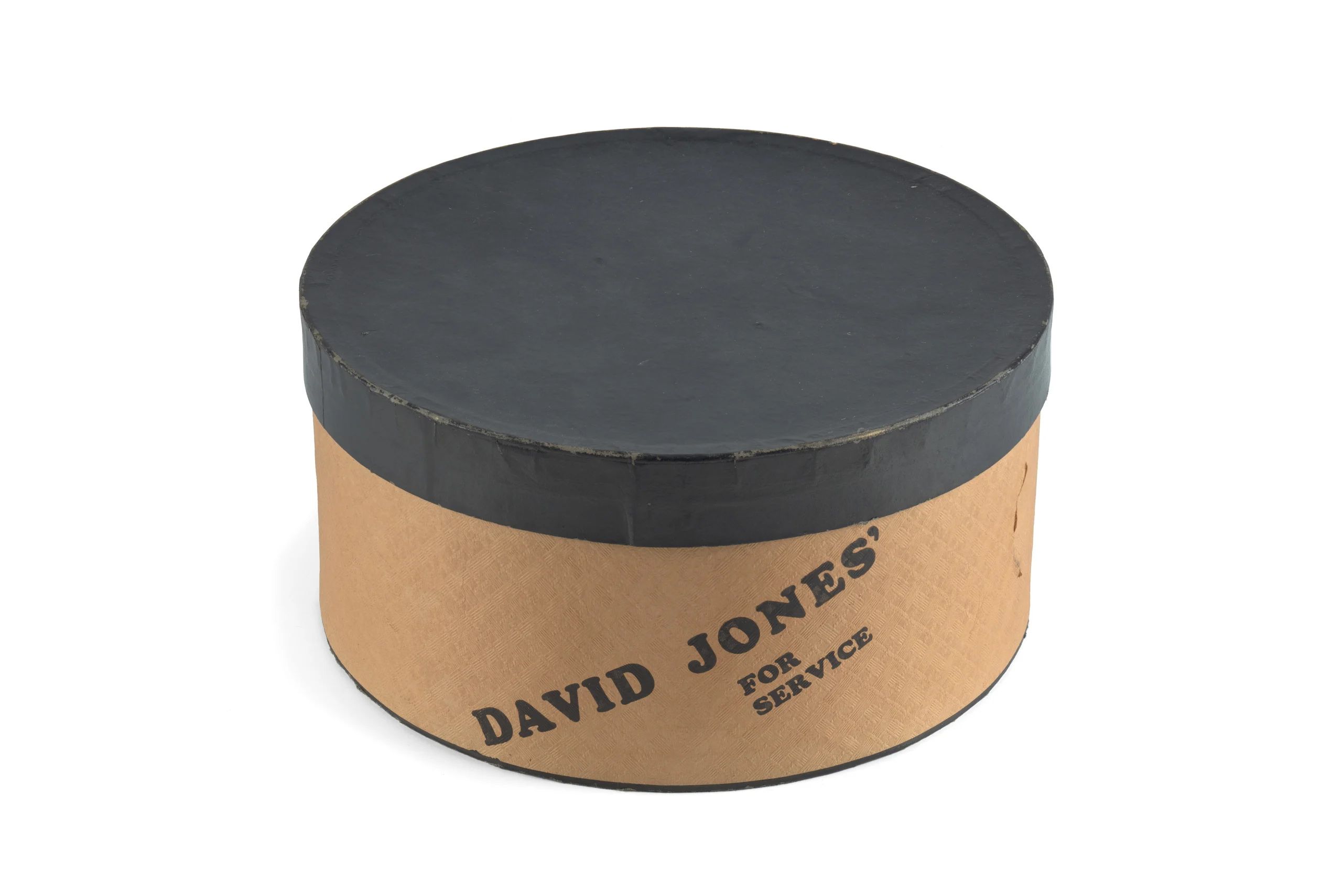 The hat box is circular, with a tan base and a dark brown lid.