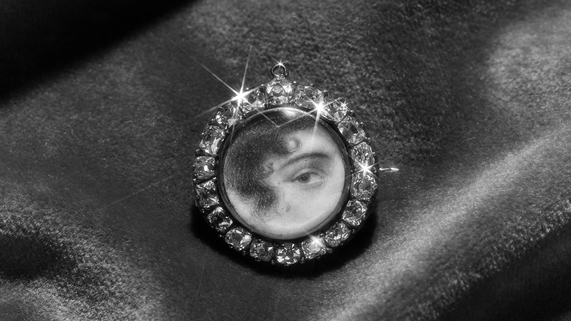 An antique brooch consisting of a round miniature portrait of an eye set around the edge with diamonds.
