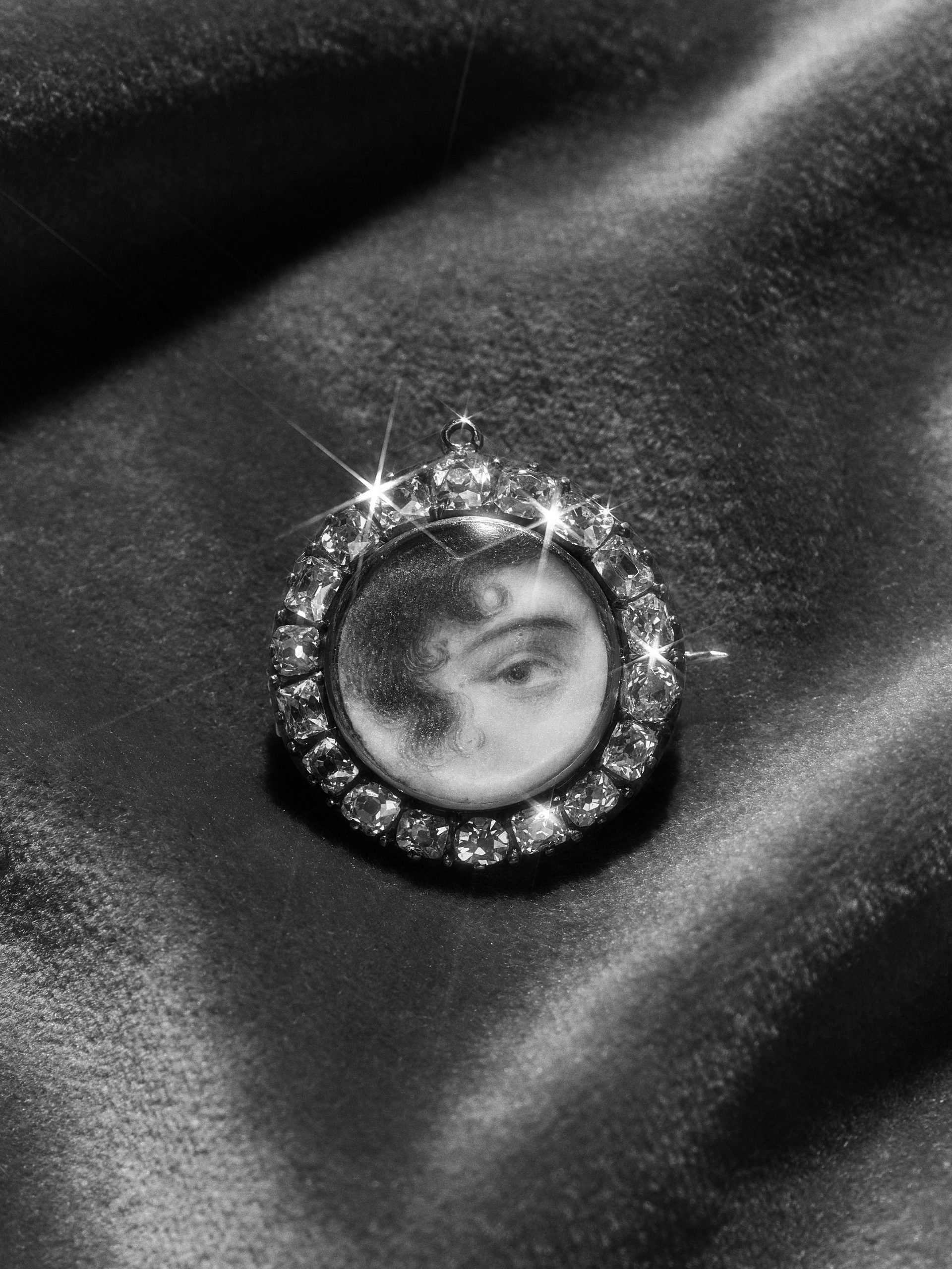 An antique brooch consisting of a round miniature portrait of an eye set around the edge with diamonds.