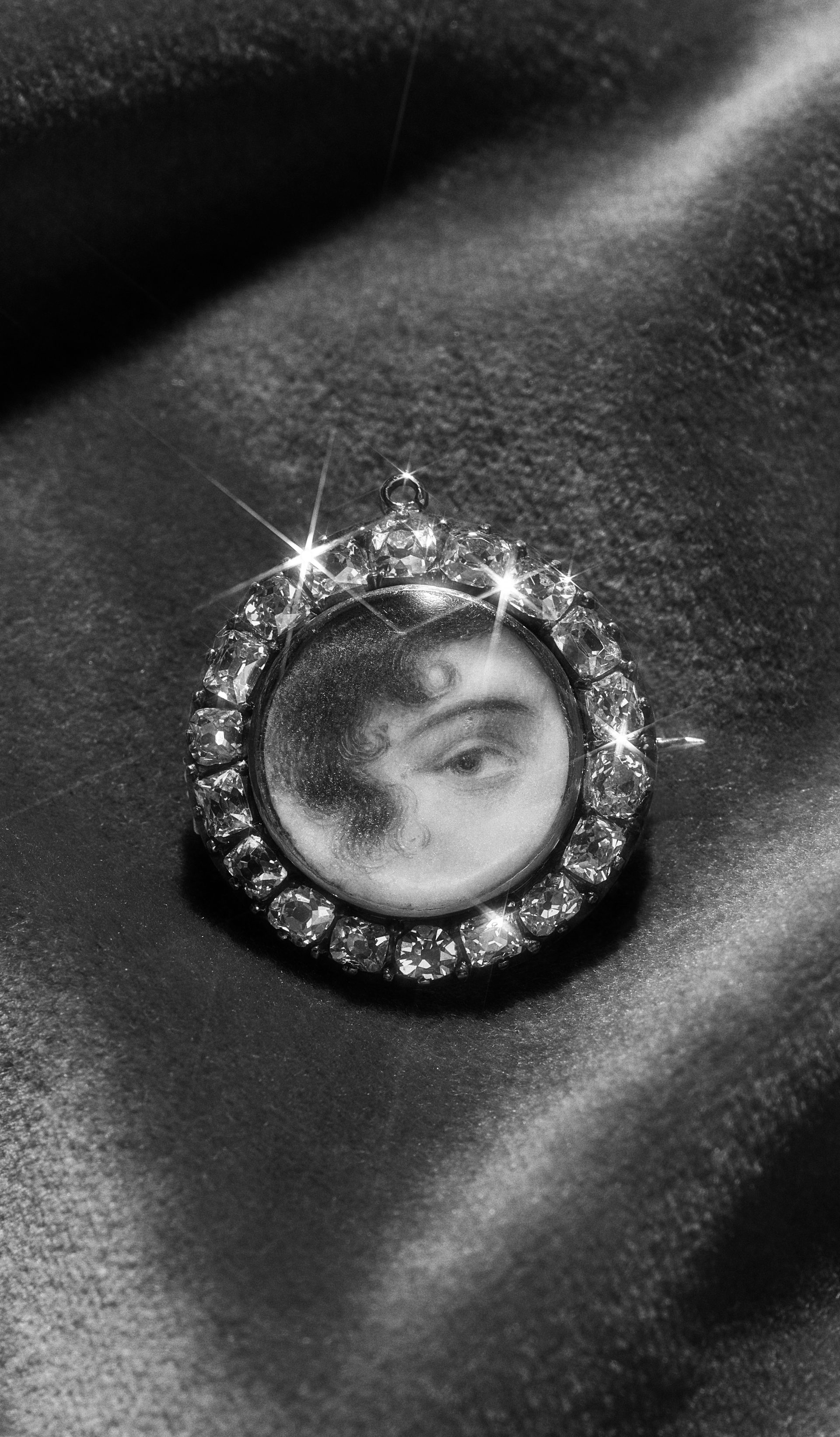 An antique brooch consisting of a round miniature portrait of an eye set around the edge with diamonds.