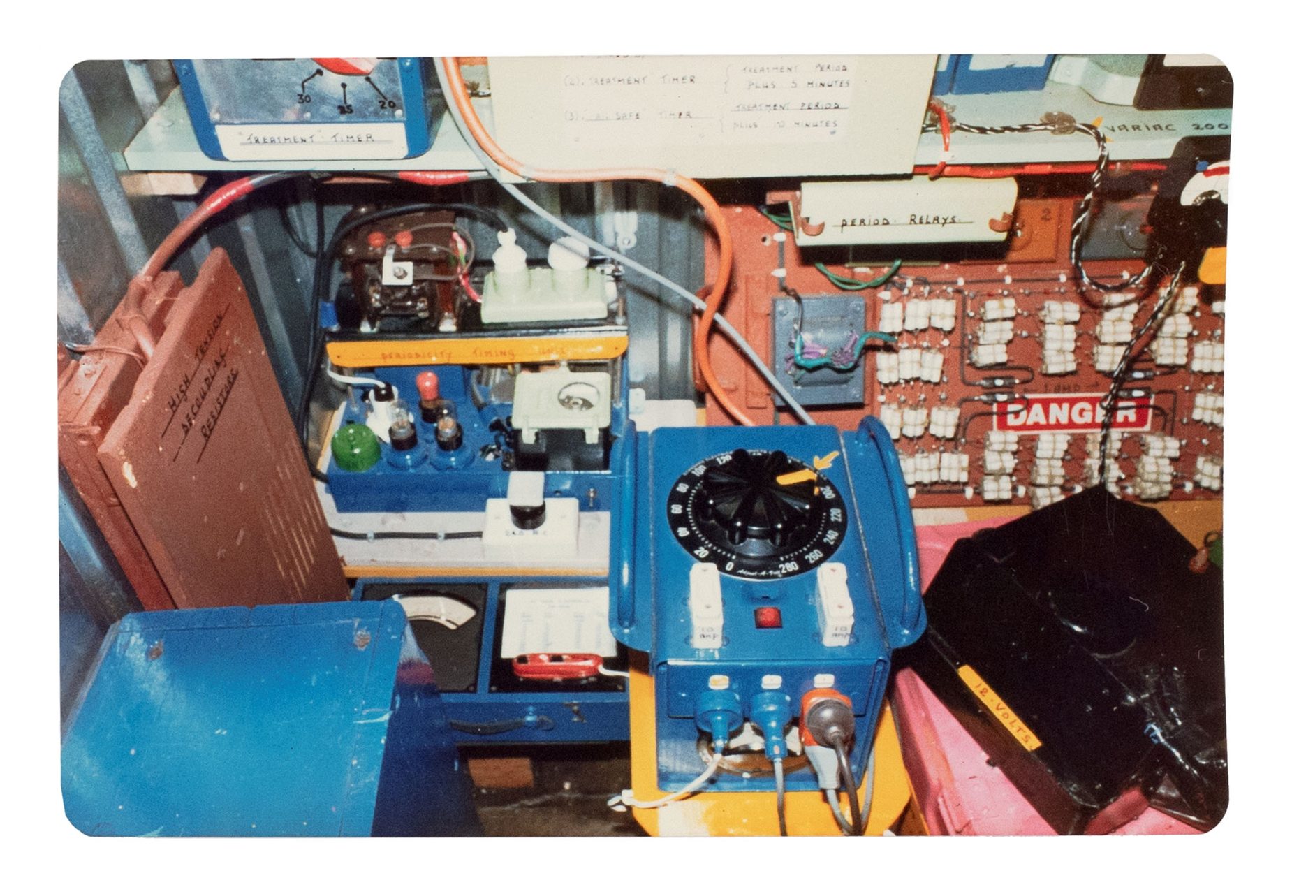 Green and yellow metal 'garden' shed containing elaborate electronic systems built into the interior. Inside the shed is a compartment which contains a seat where the user can sit and be suffused with radio waves produced by the electronic system.